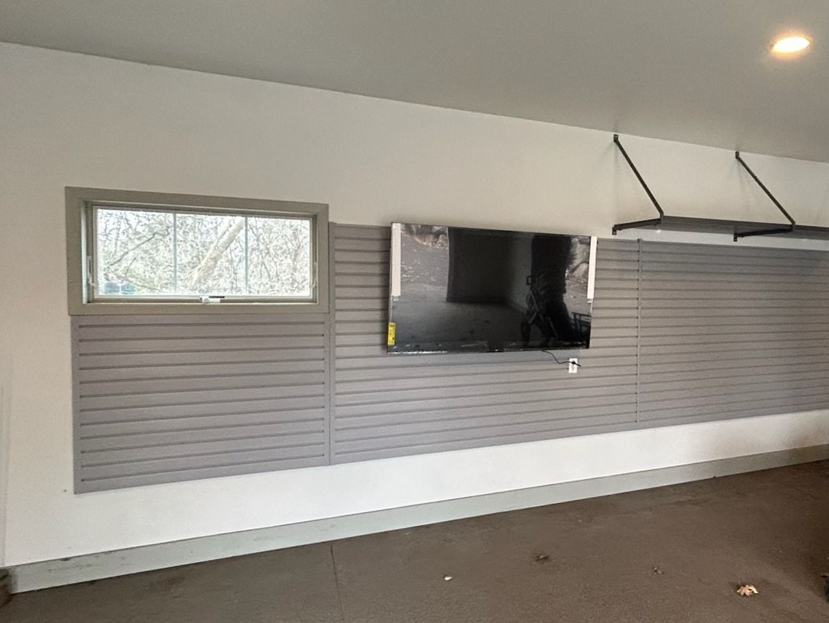 Living room wall with mounted TV, gray blinds, and a small window under a white ceiling