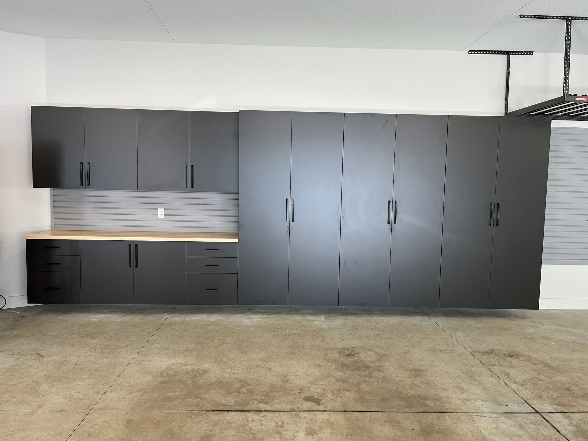 Garage wall with dark gray cabinets, wood countertop, and concrete floor