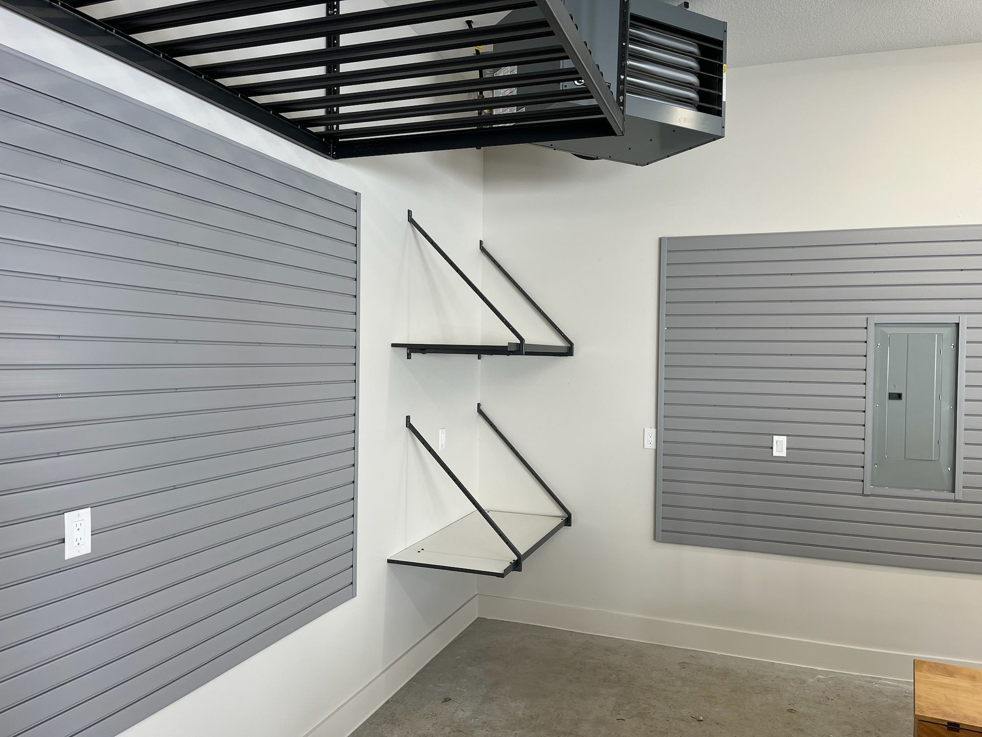 Modern interior with gray slat walls, black wall shelves, and a mezzanine staircase.