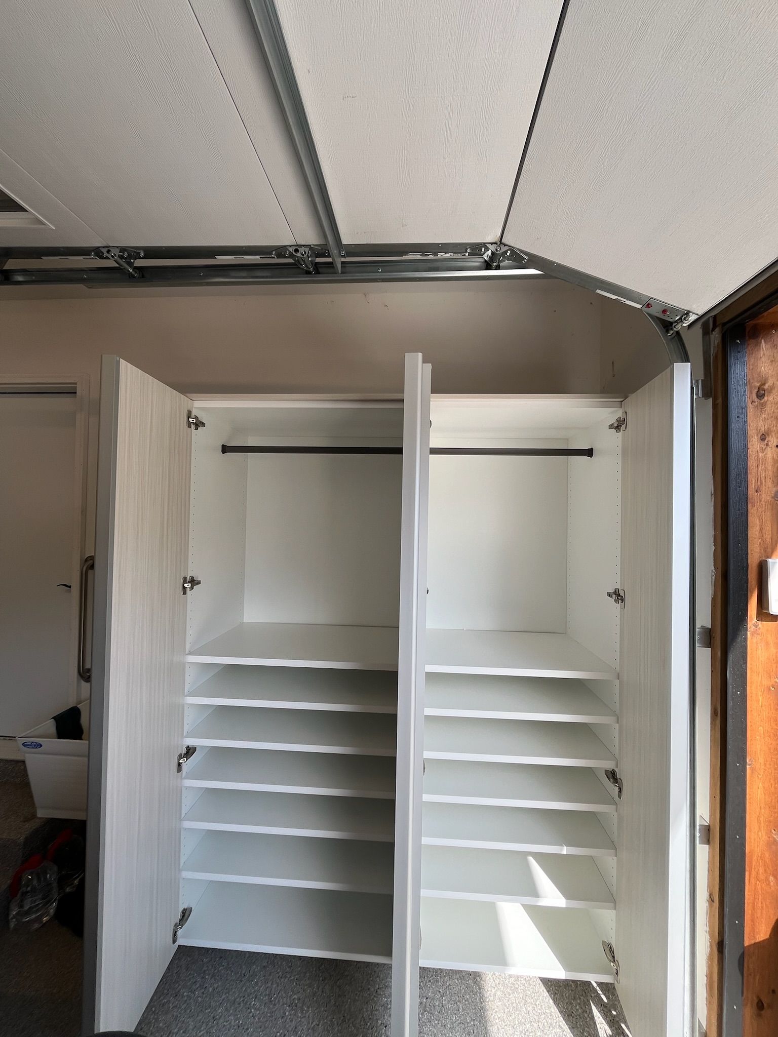 Open closet with white shelving and a partially open door in a small room.