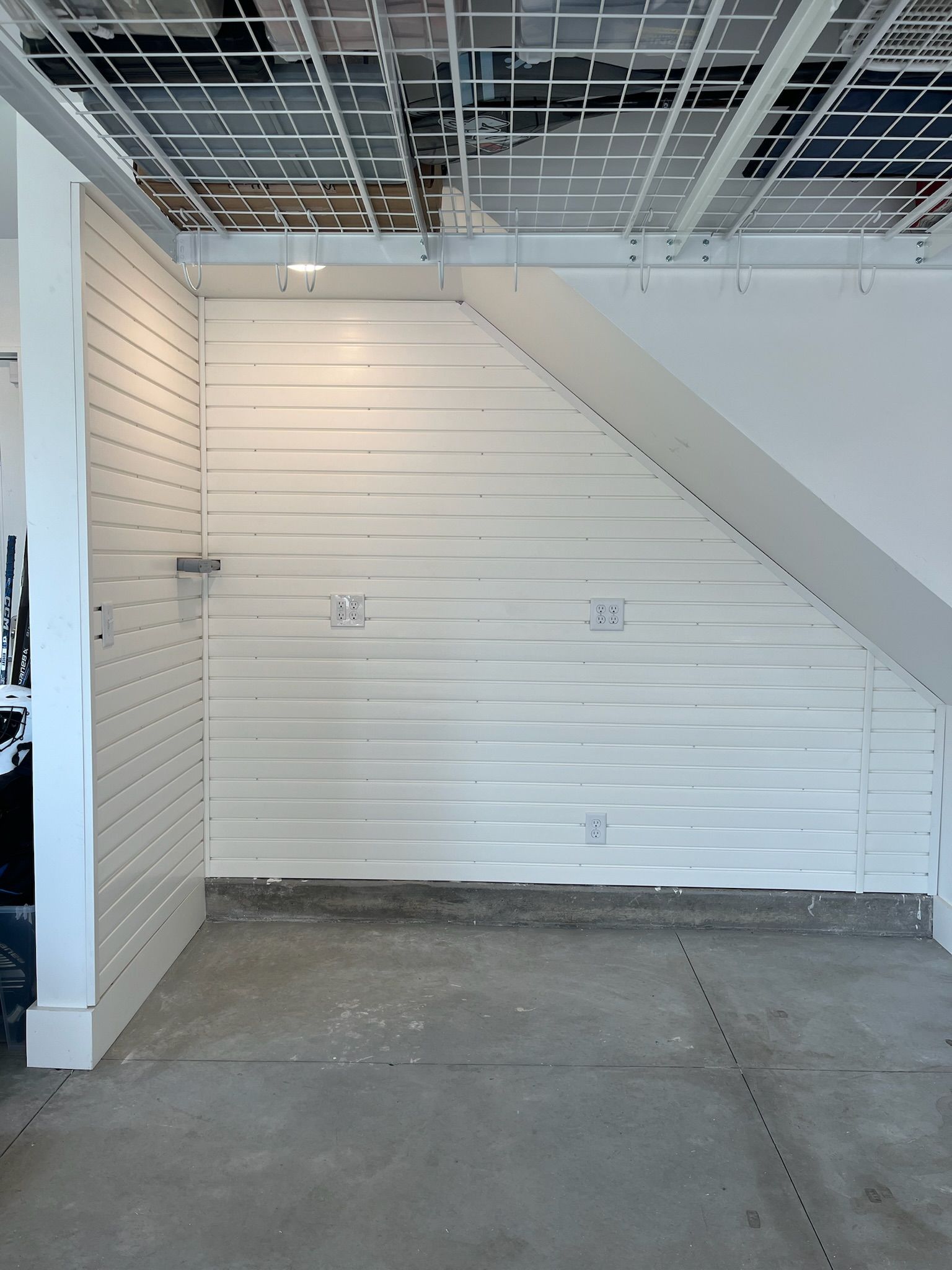 Empty retail space with white slat walls, exposed ceiling grid, and concrete floor