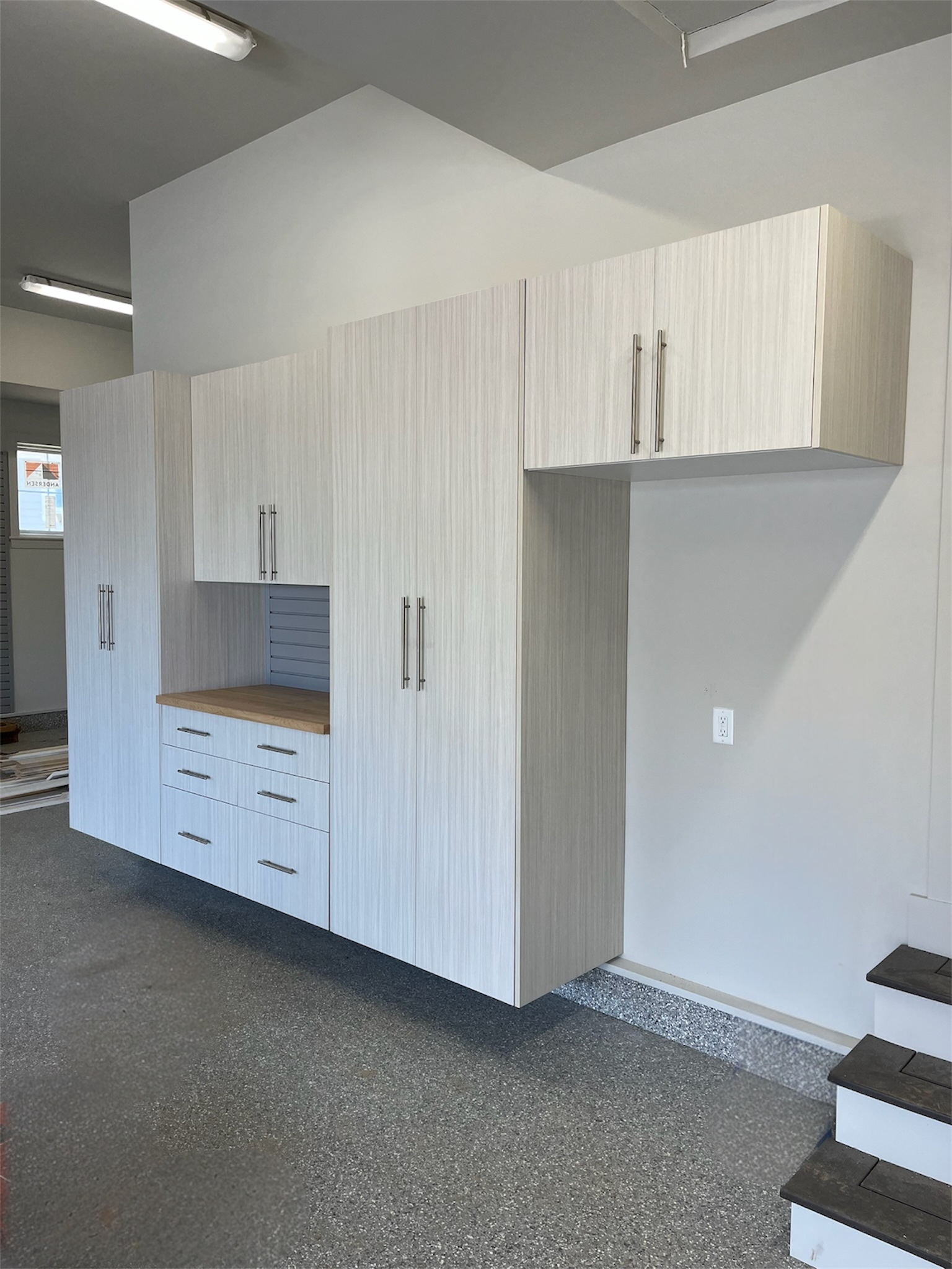 Built-in white storage cabinets with drawers and upper cupboards in a gray room