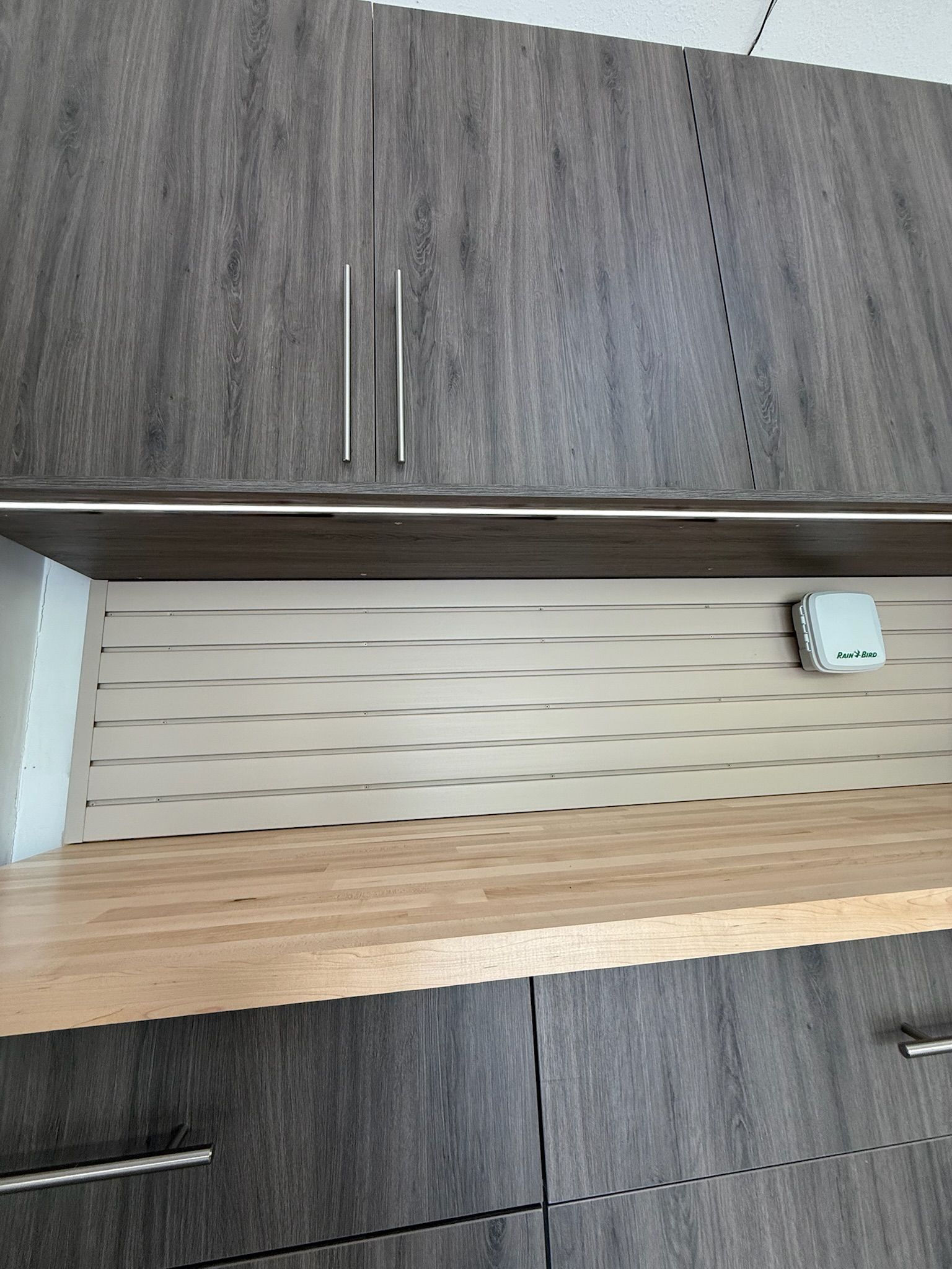 Wood-grain cabinets with a beige shelf and small white outlet on the right.