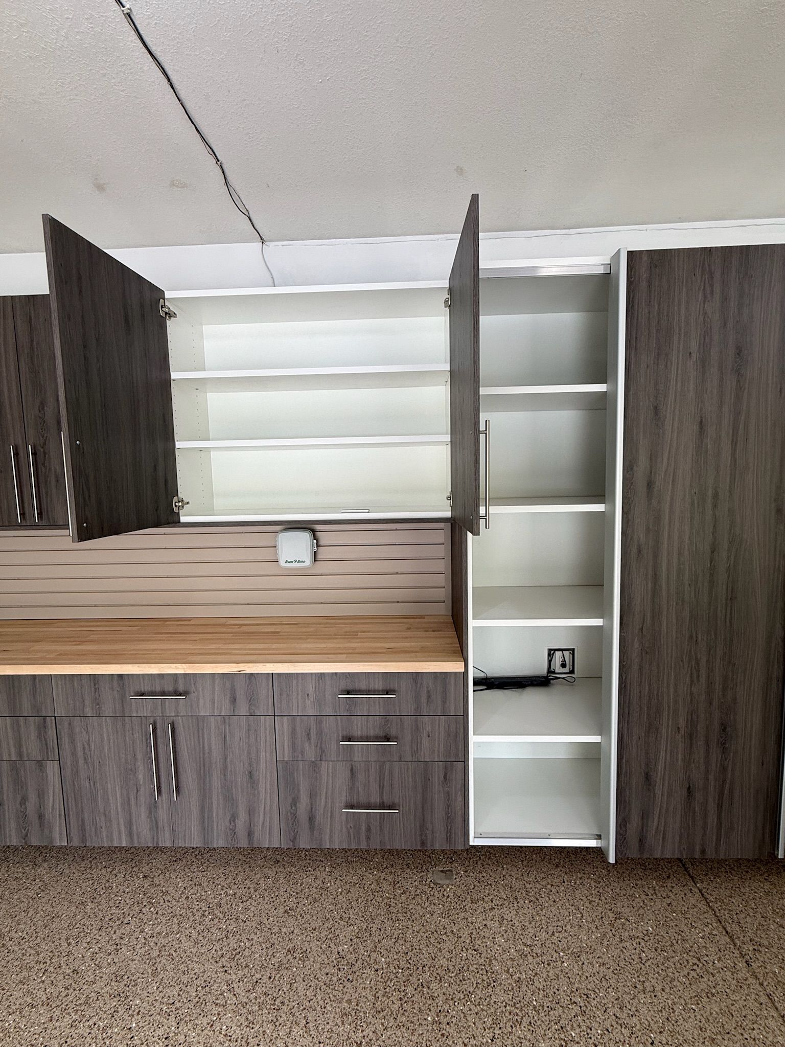Built-in wood cabinetry with open shelves and a countertop in a small room with carpeted floor.