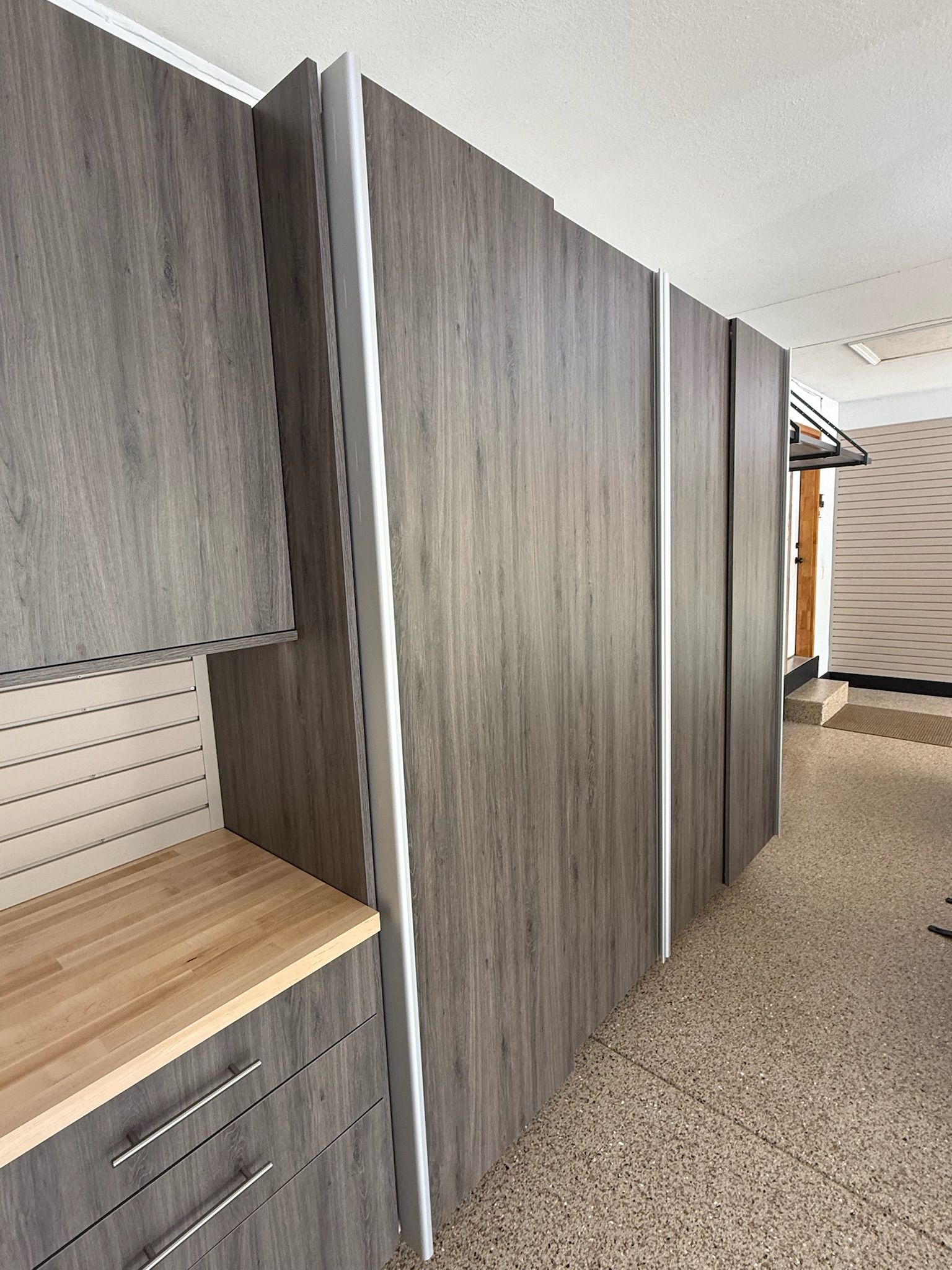 Hallway with gray wood cabinets and a light wood countertop, seen from a carpeted interior space