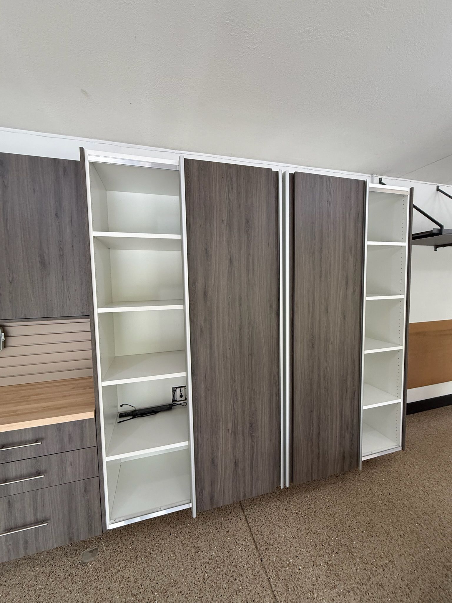 Tall gray and white storage cabinets with open shelves in a carpeted room