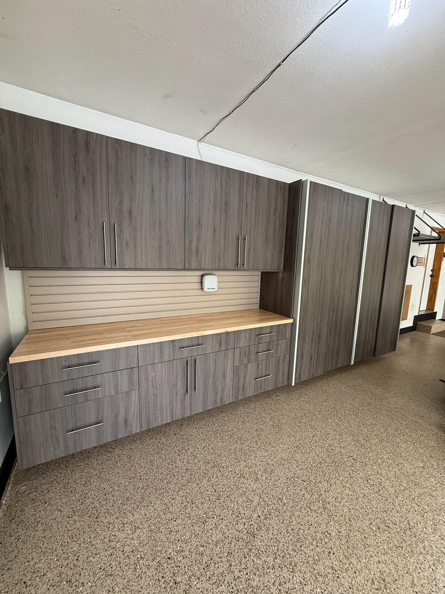 Empty room with gray wood cabinets, light countertop, and beige speckled floor under a slanted ceiling