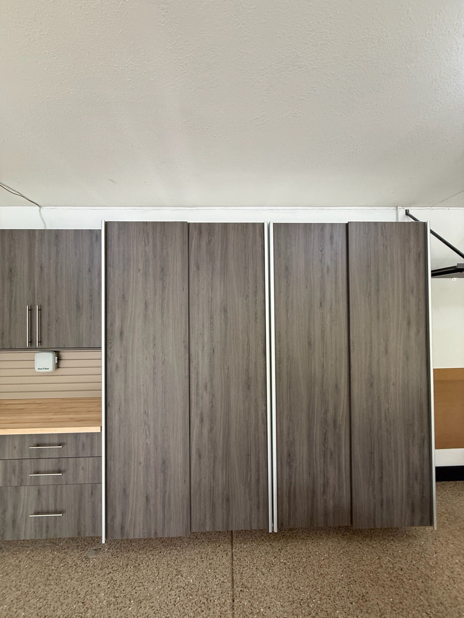 Kitchen cabinetry with gray wood-grain cabinets and a light wood countertop beneath a slanted ceiling