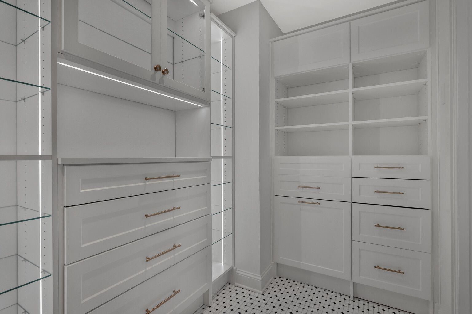 A walk in closet with white cabinets , drawers , and shelves.