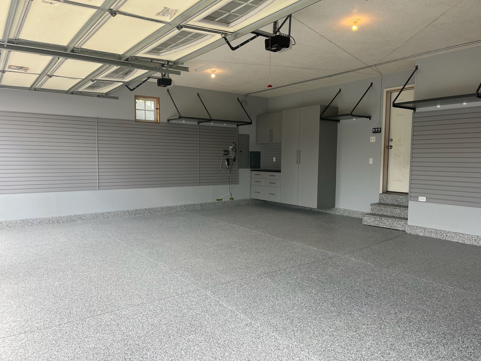 Empty garage with closed gray shutters and speckled epoxy floor, viewed from inside.