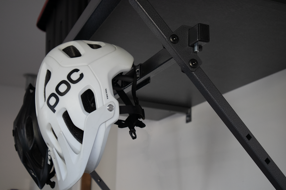 White and black POC bike helmet hanging from a shelf.