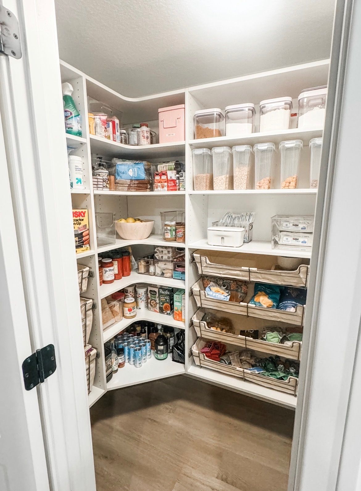 Walk-in pantry shelves stocked with jars, cans, baskets, and storage containers