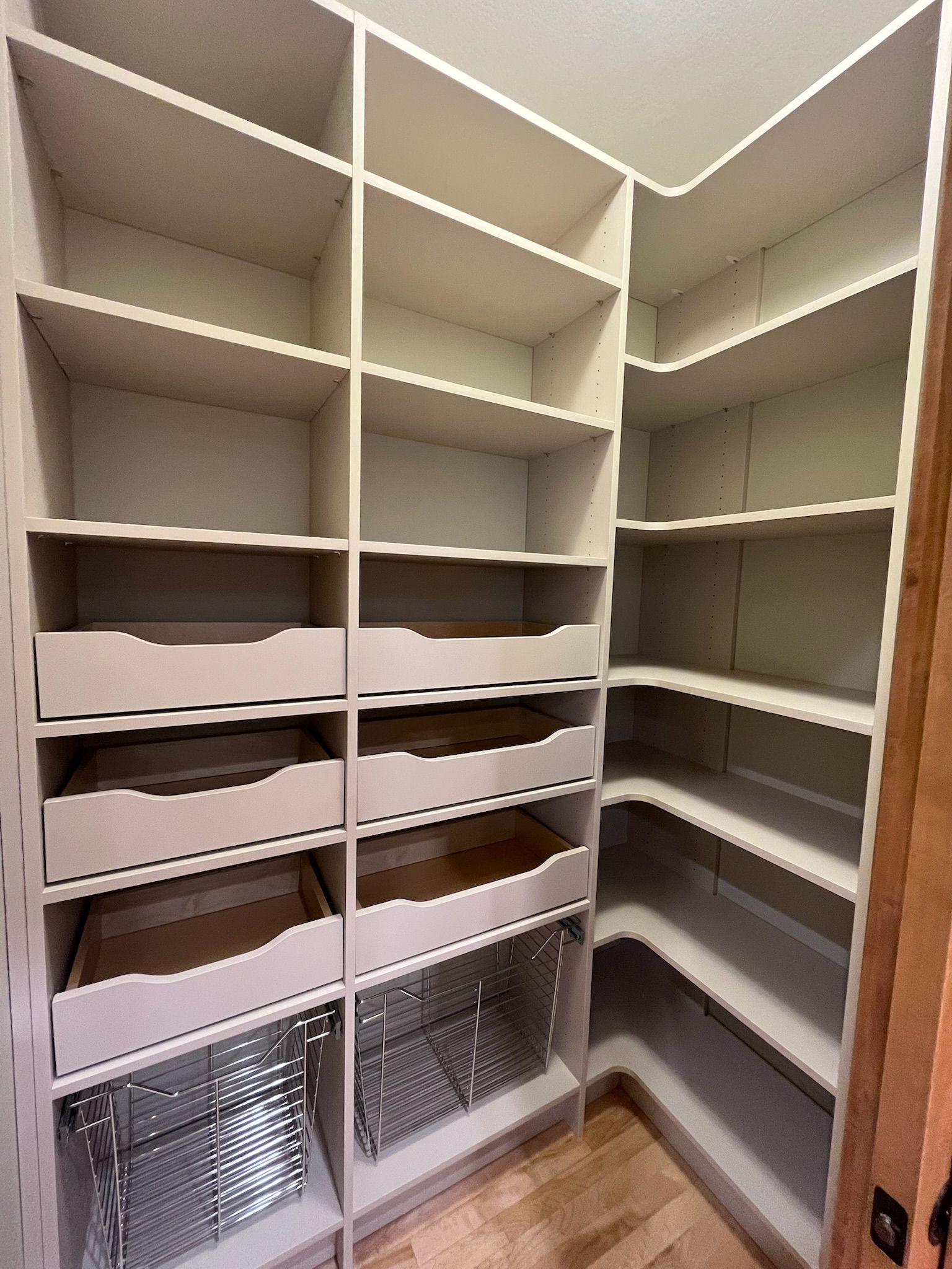 Built-in white closet with shelves, hanging rods, drawers, and wire baskets, viewed from inside.
