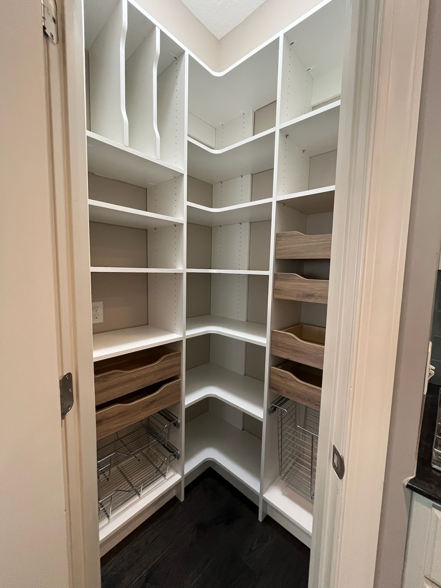 White walk-in closet with built-in shelving, drawers, and hanging rods, viewed from the doorway.
