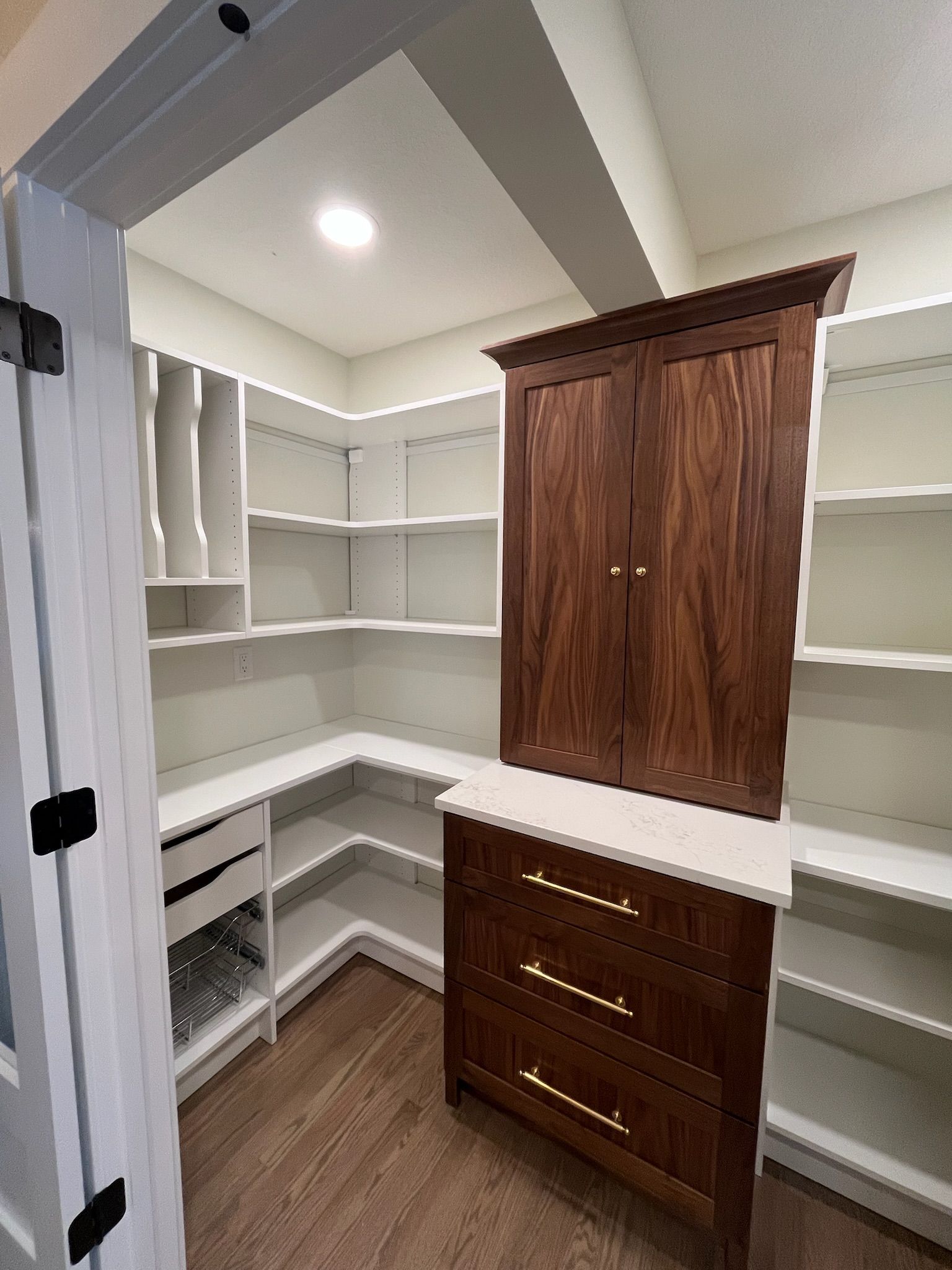 Walk-in closet with white shelving, a wood cabinet, and a dresser under recessed ceiling lights