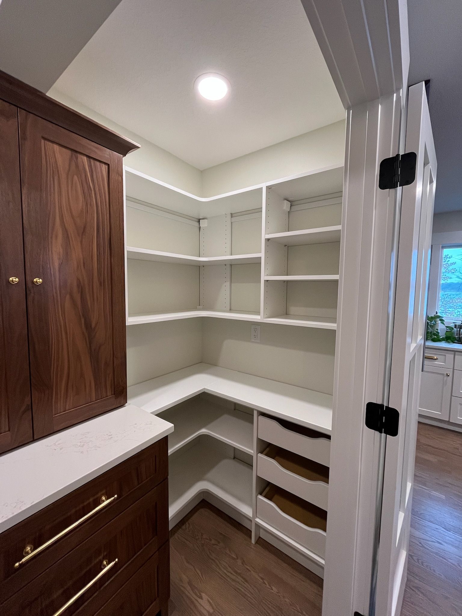 Empty walk-in closet with white shelves, built-in drawers, and a wood cabinet.