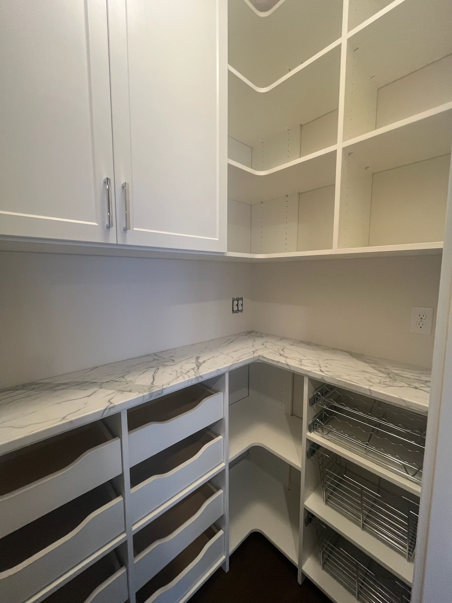 White corner pantry with open shelves, drawers, and cabinets in a clean, bright closet-style room