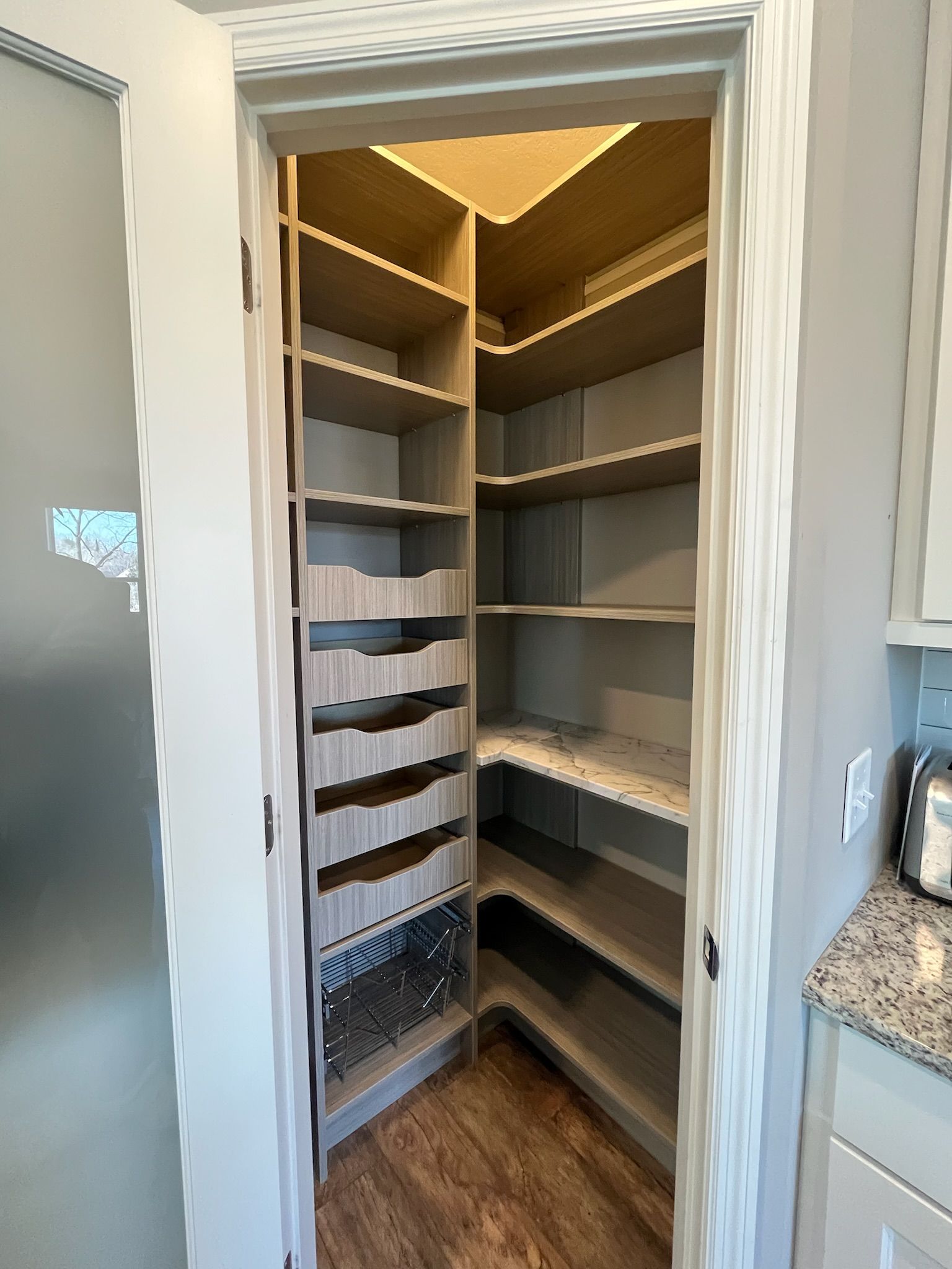 Empty white pantry with corner shelves and warm under-shelf lighting