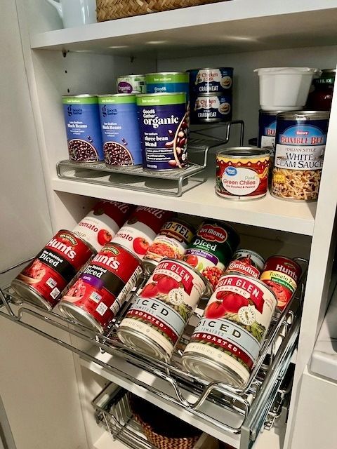 Pantry shelf with canned goods and jars, including red-and-white soup cans on pull-out wire racks