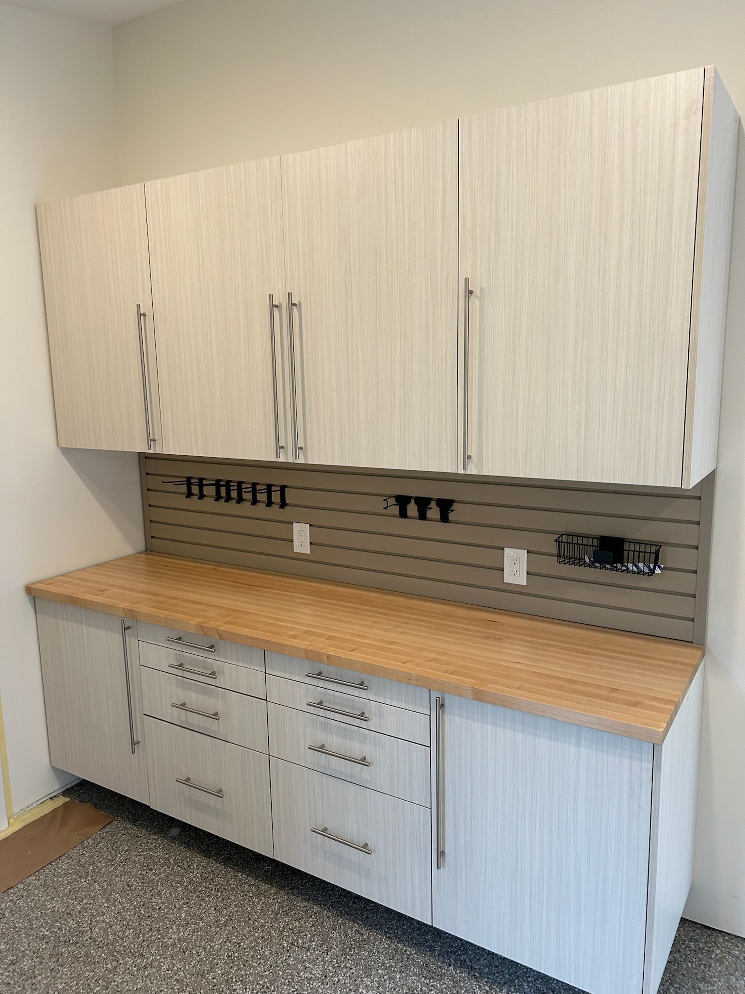 White kitchen cabinets and countertop in a small room, with a sink and tiled backsplash.