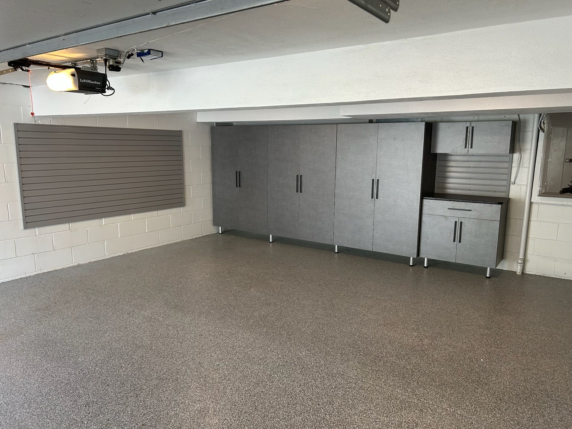 Empty gray garage or storage room with cabinets along the back wall and speckled floor
