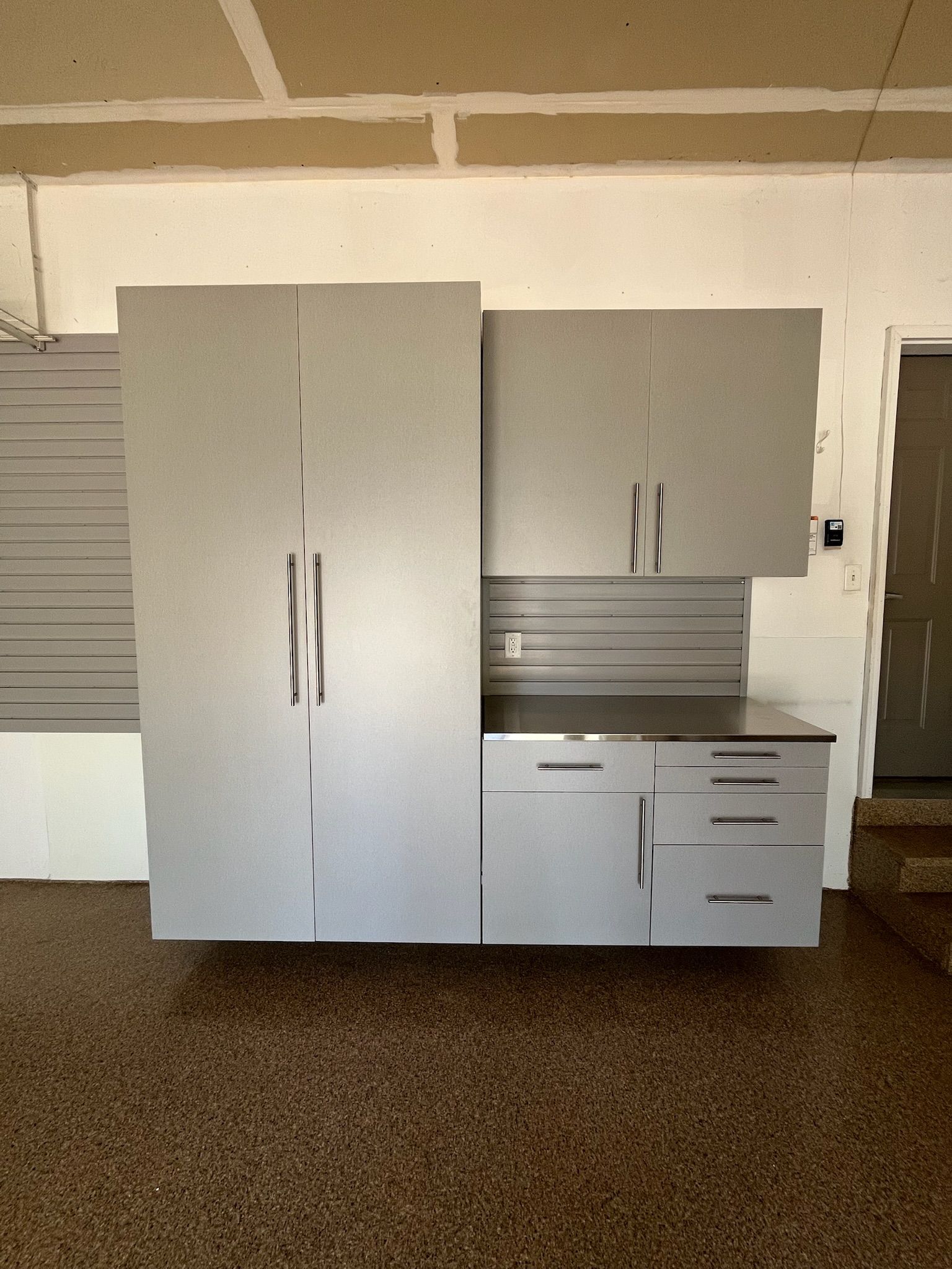 Gray storage cabinets and drawers against a wall in an empty room.