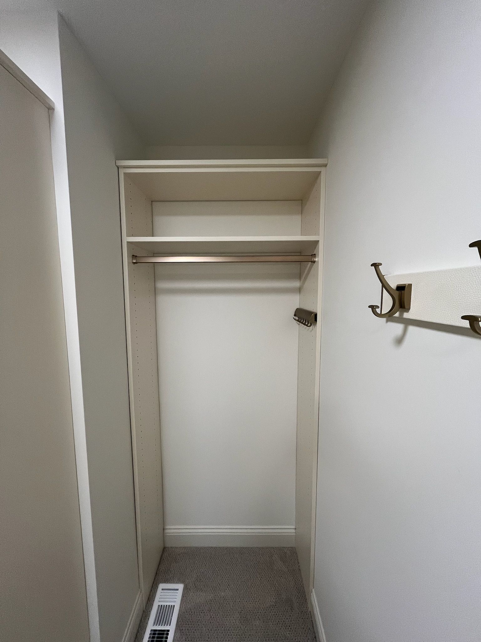 Narrow white closet hallway with wire shelving and a wall-mounted hook.