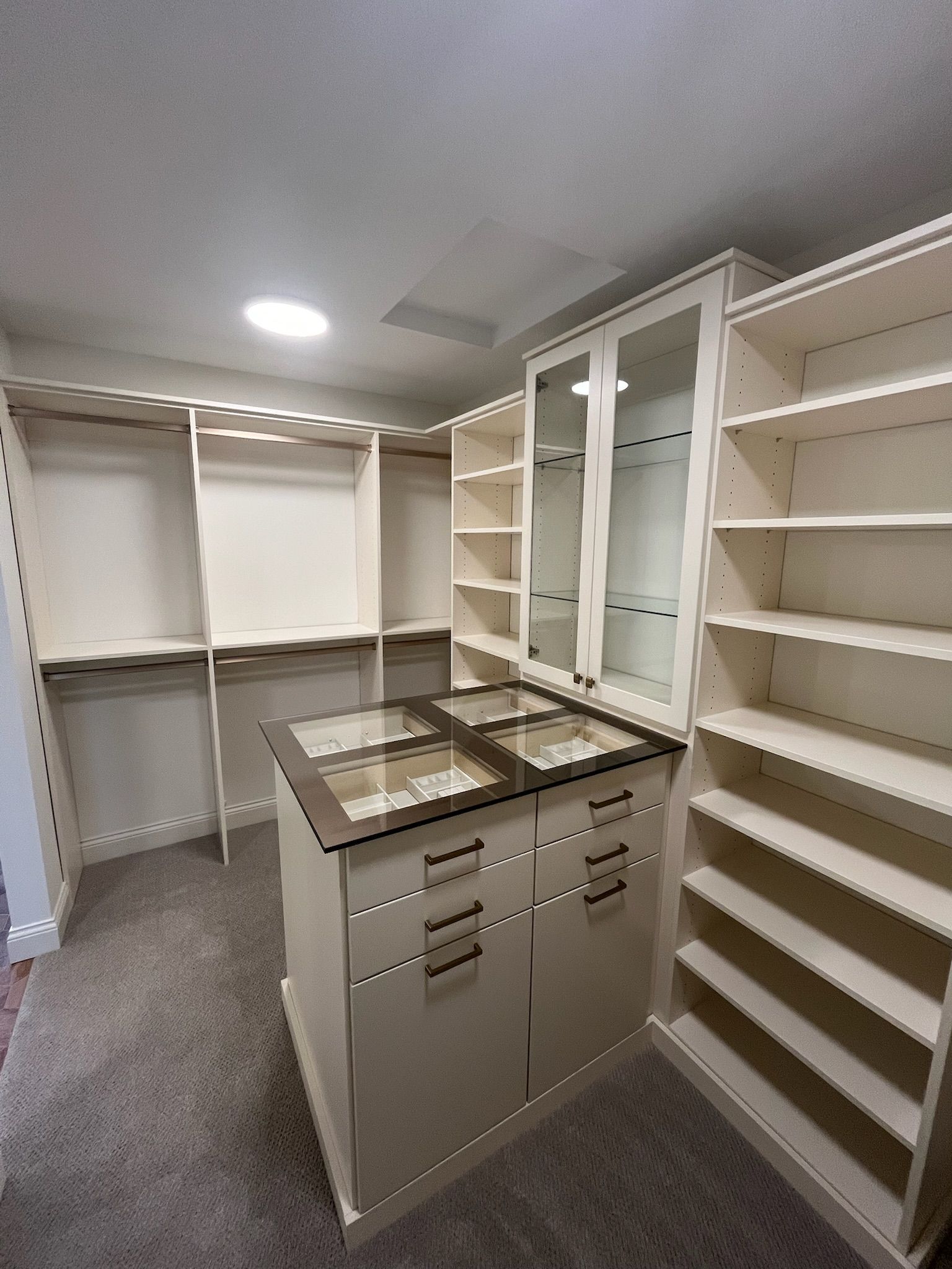 Spacious walk-in closet with white shelving, hanging rods, and a central island with drawers.