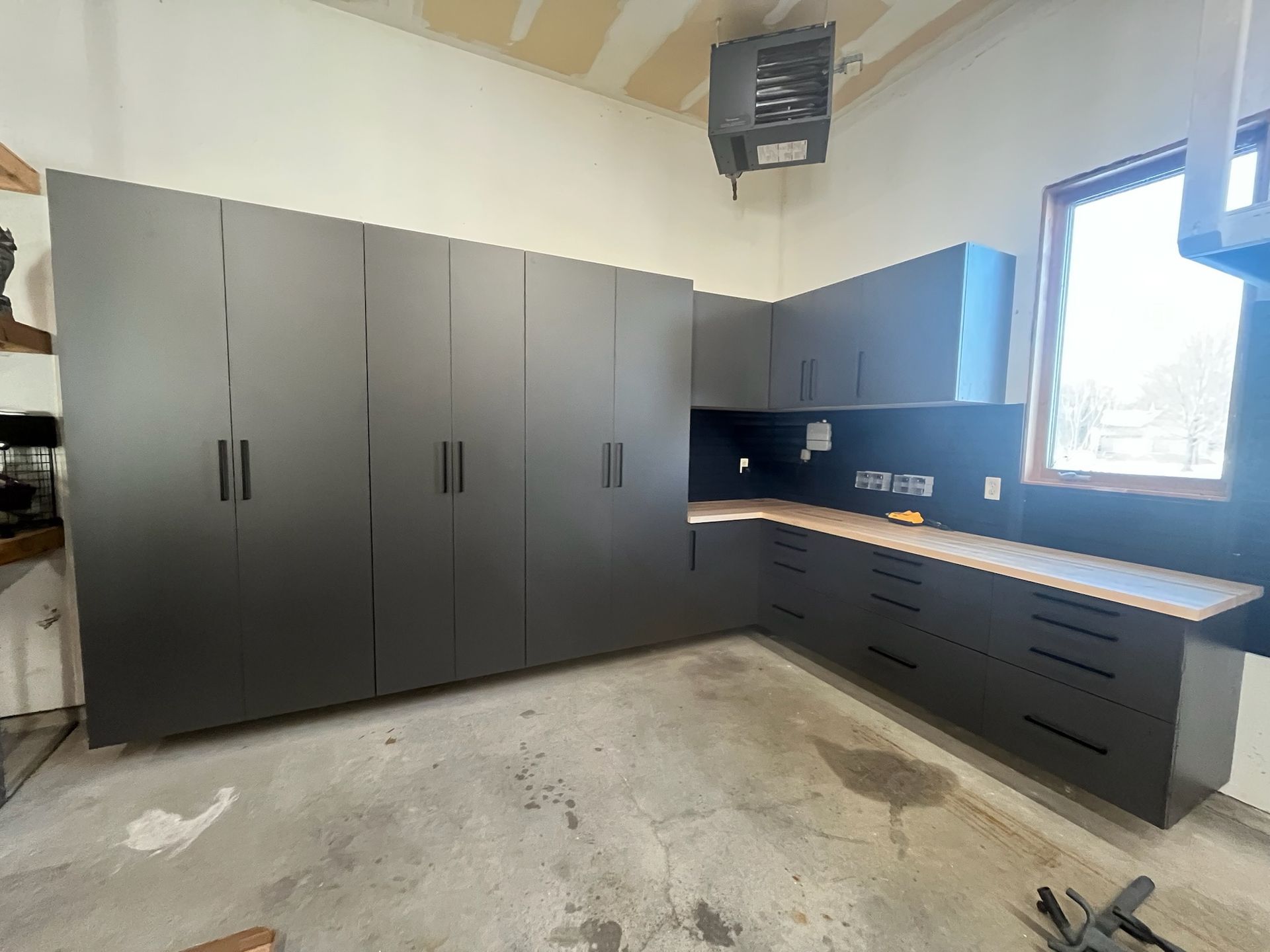 Modern kitchen with matte gray cabinets, black countertops, and a large window on the right.