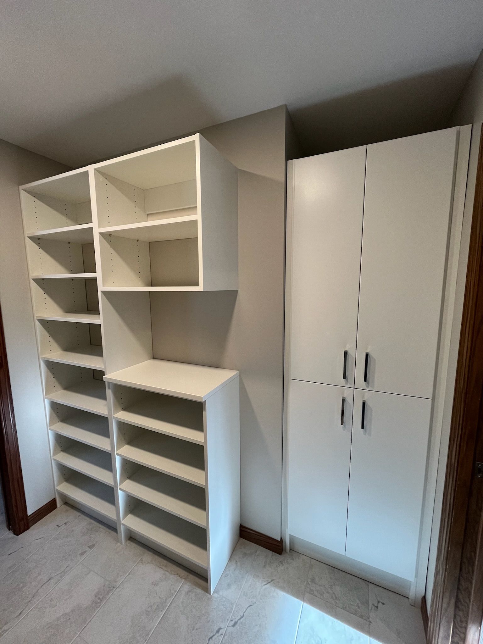 White built-in shelving and cabinets in a hallway, with open cubbies and a tall closet.