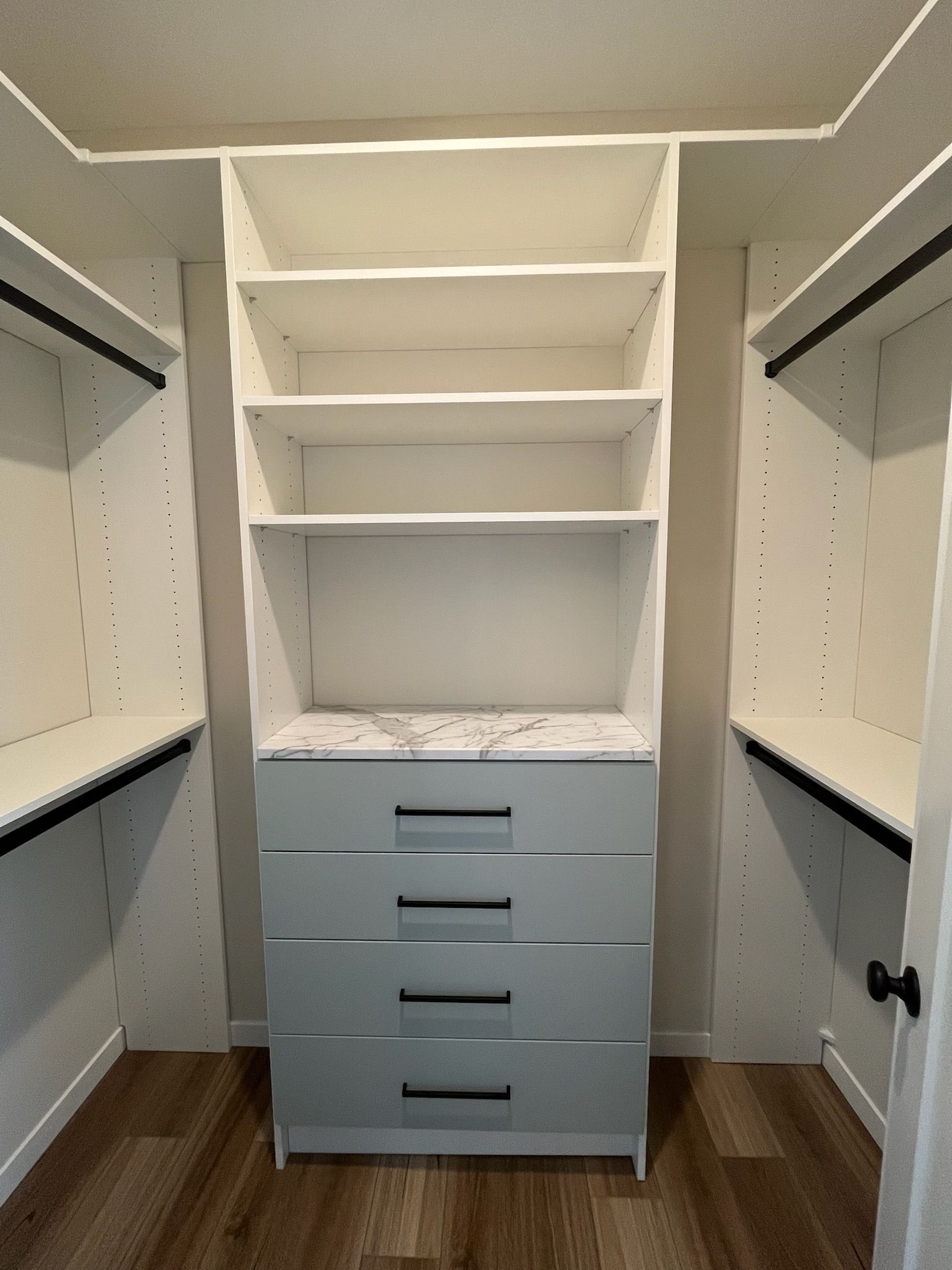 Walk-in closet with white shelves and gray drawers, showing open storage space and hanging rods on both sides