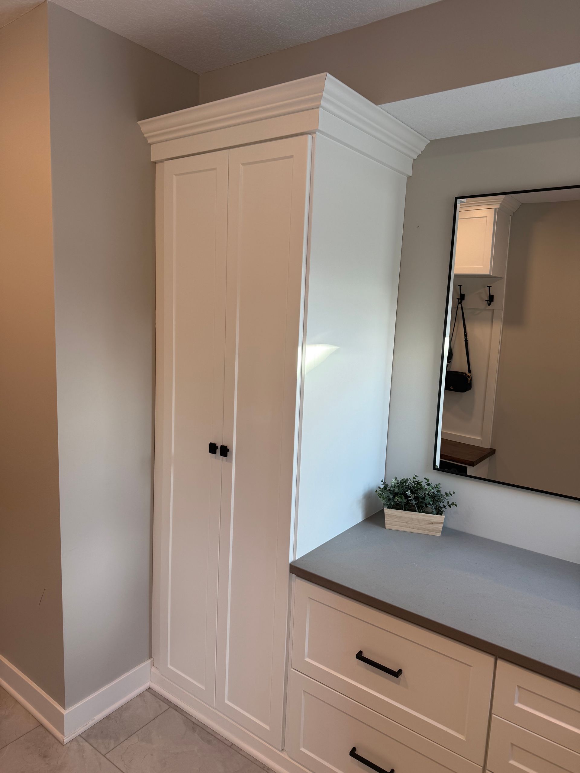 Built-in white cabinet beside a dresser with mirror in a neutral-toned bedroom