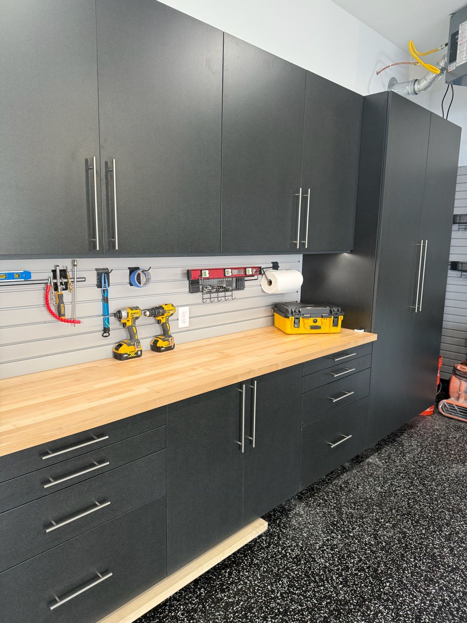 Black garage cabinets and workbench with tools in a clean workshop.