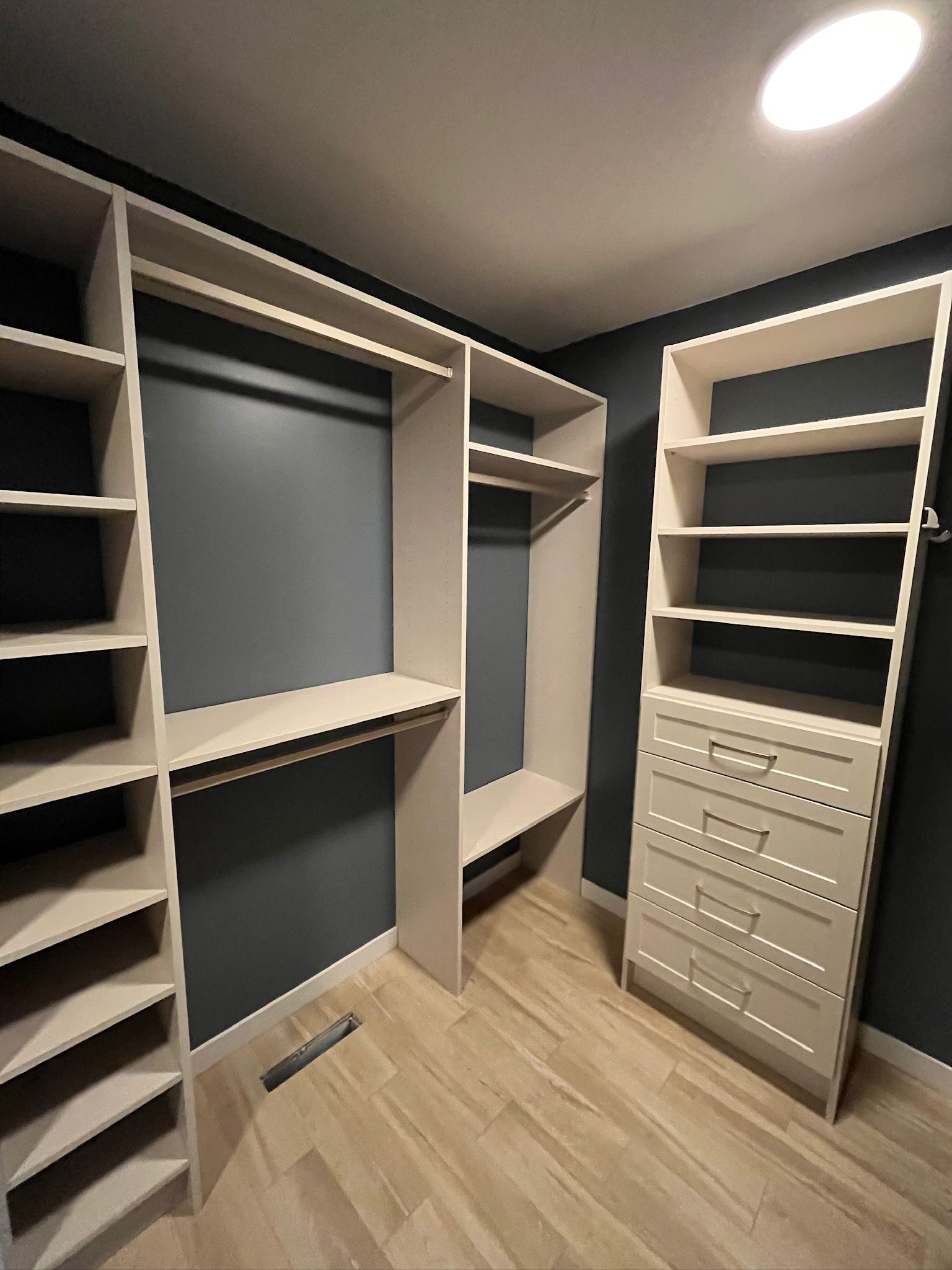 Walk-in closet with built-in shelves, hanging rods, drawers, and light wood flooring