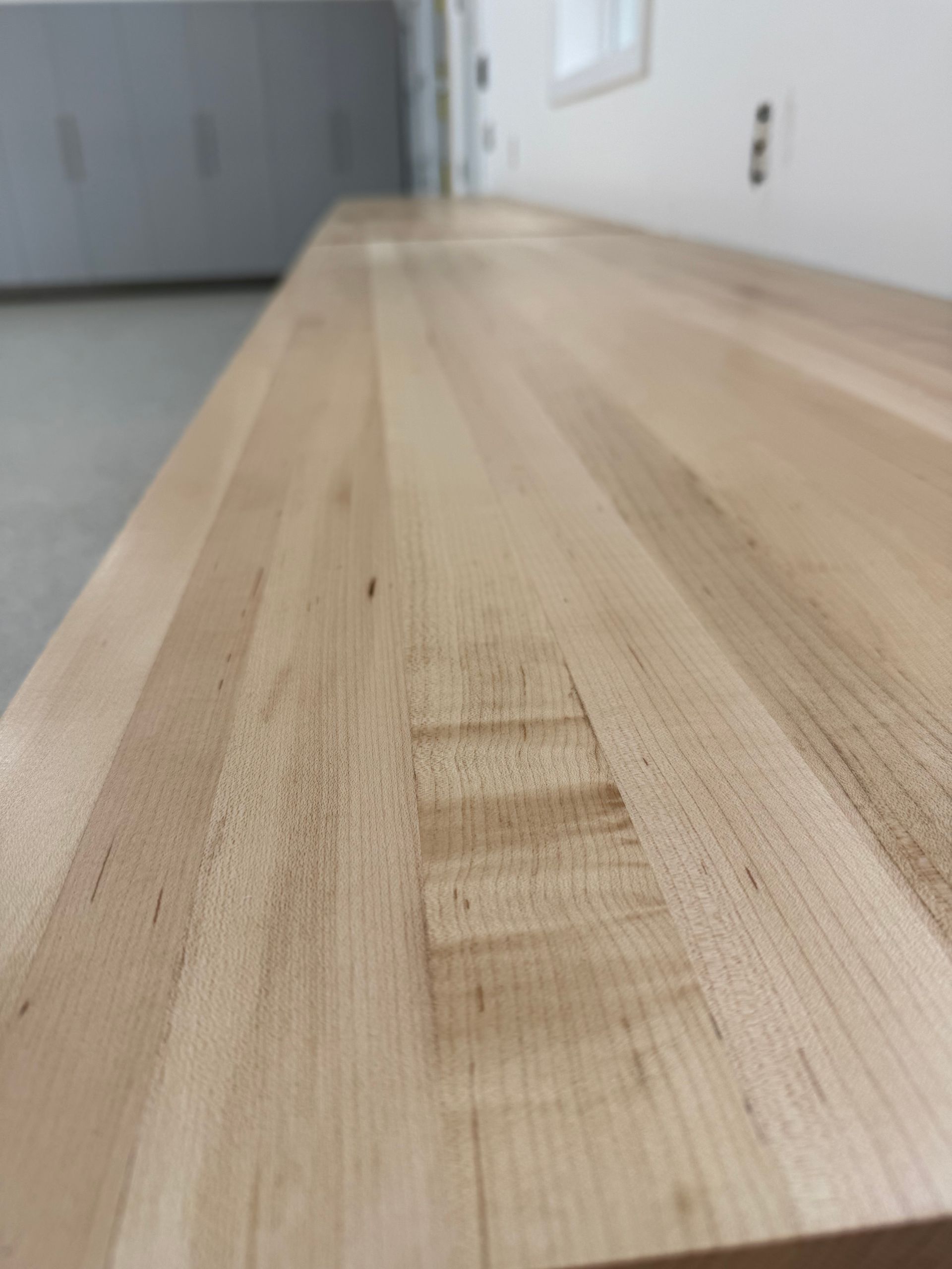 Close-up of a light wood tabletop with a visible scratch or repaired patch in the center.