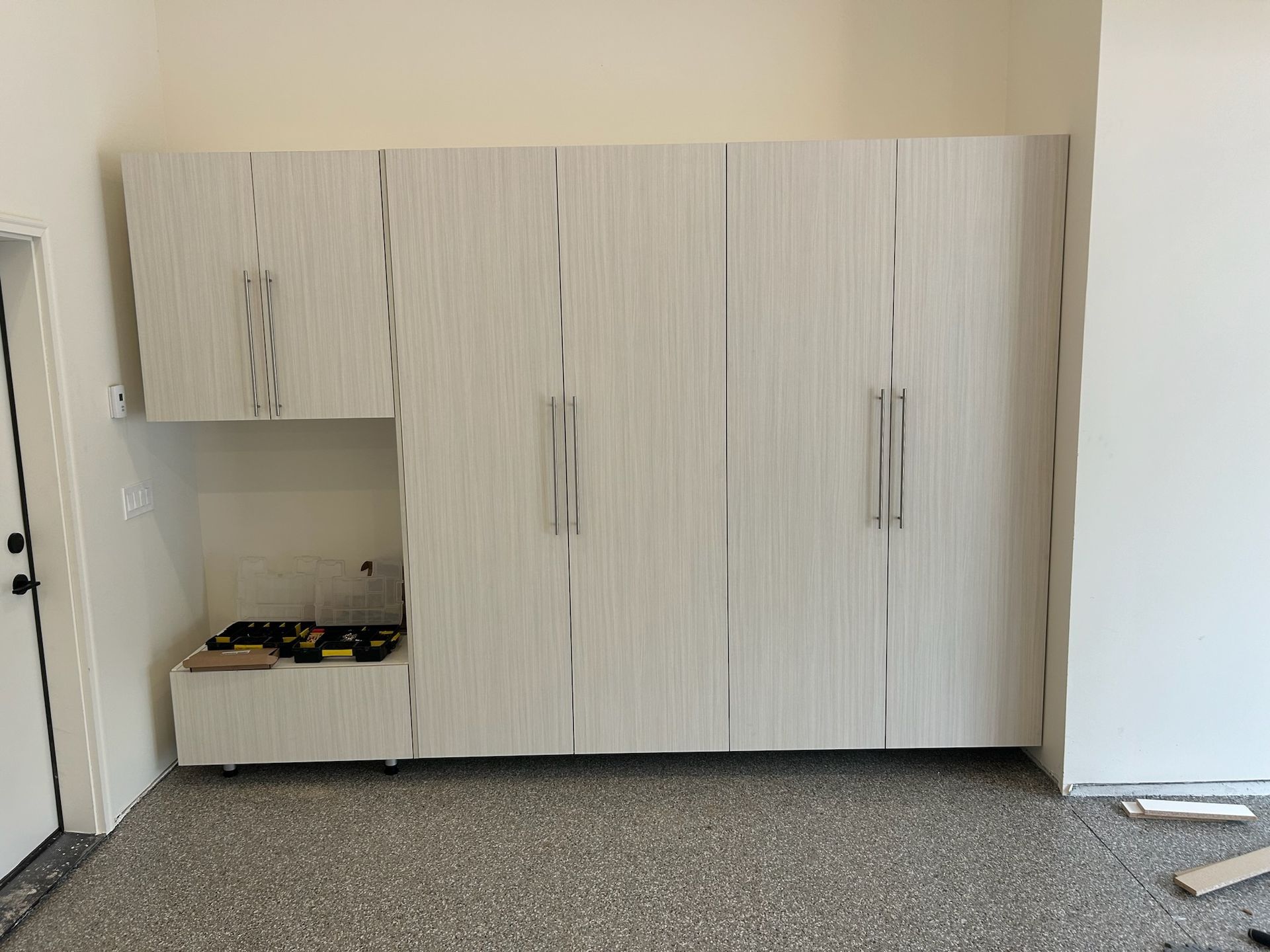 White cabinets and storage units against a wall in a bare room with carpeted floor