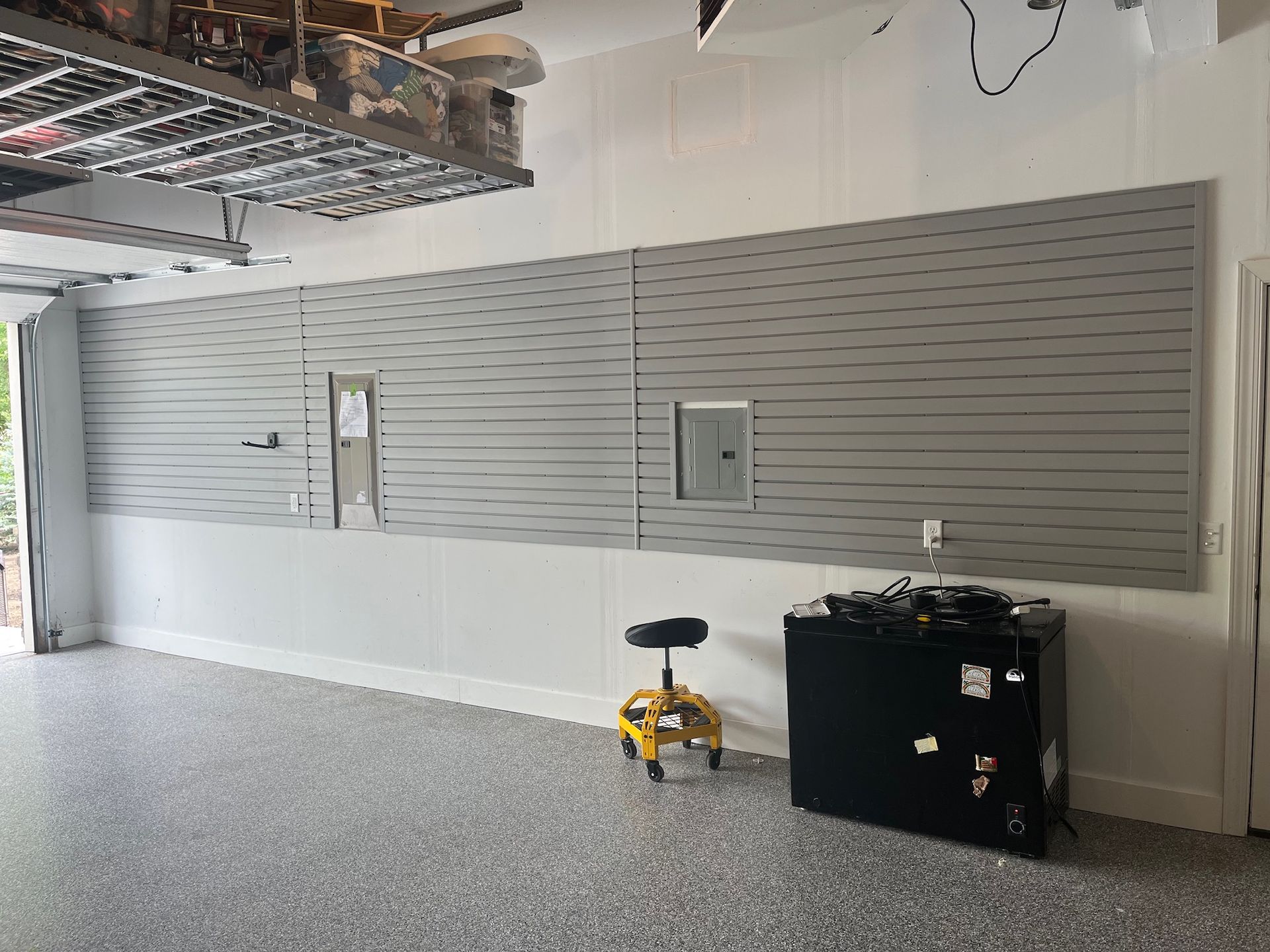 Empty retail space with gray slatwall display panels and a yellow floor buffer on the carpeted floor