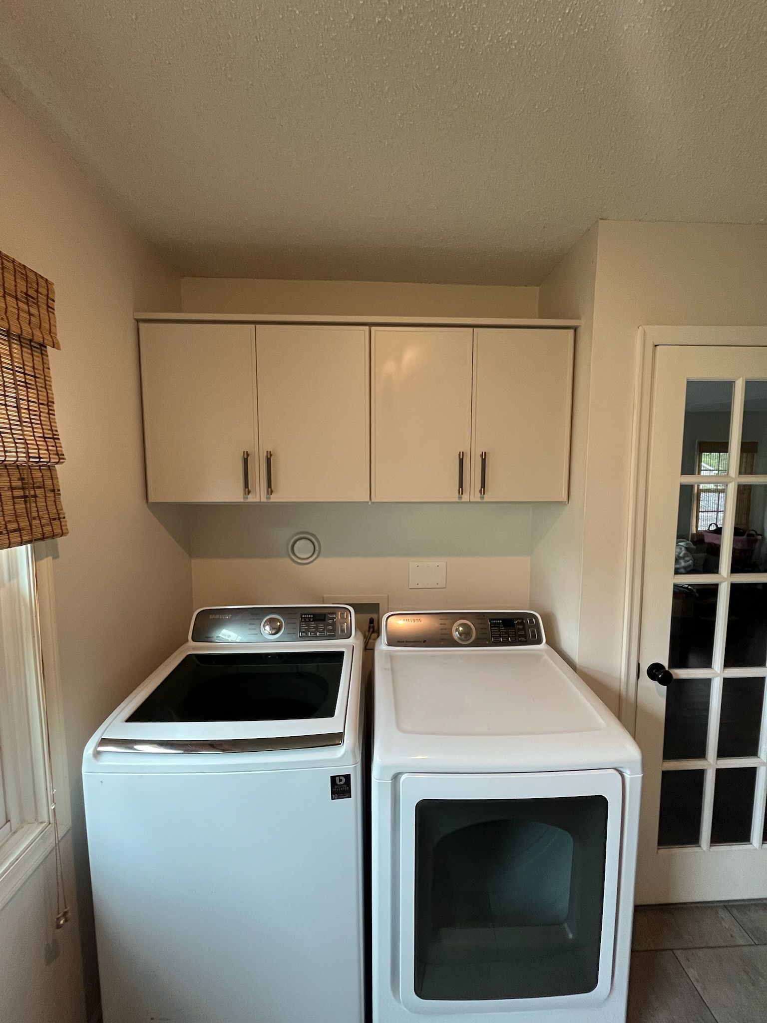 Laundry room with a white washer, dryer, and wall cabinets in a narrow nook