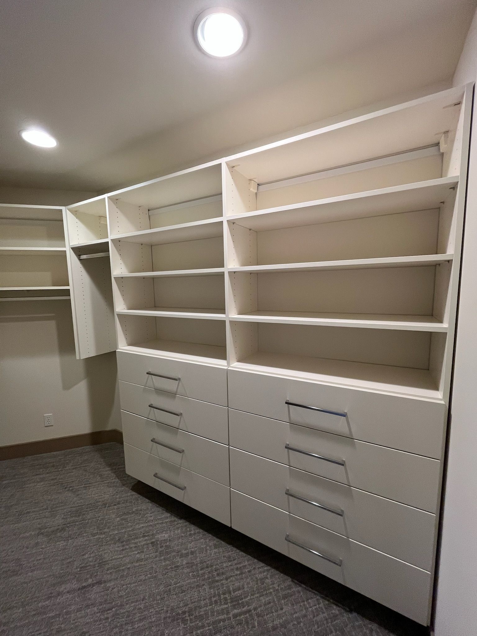 Built-in white closet shelves and drawers in a small walk-in storage room