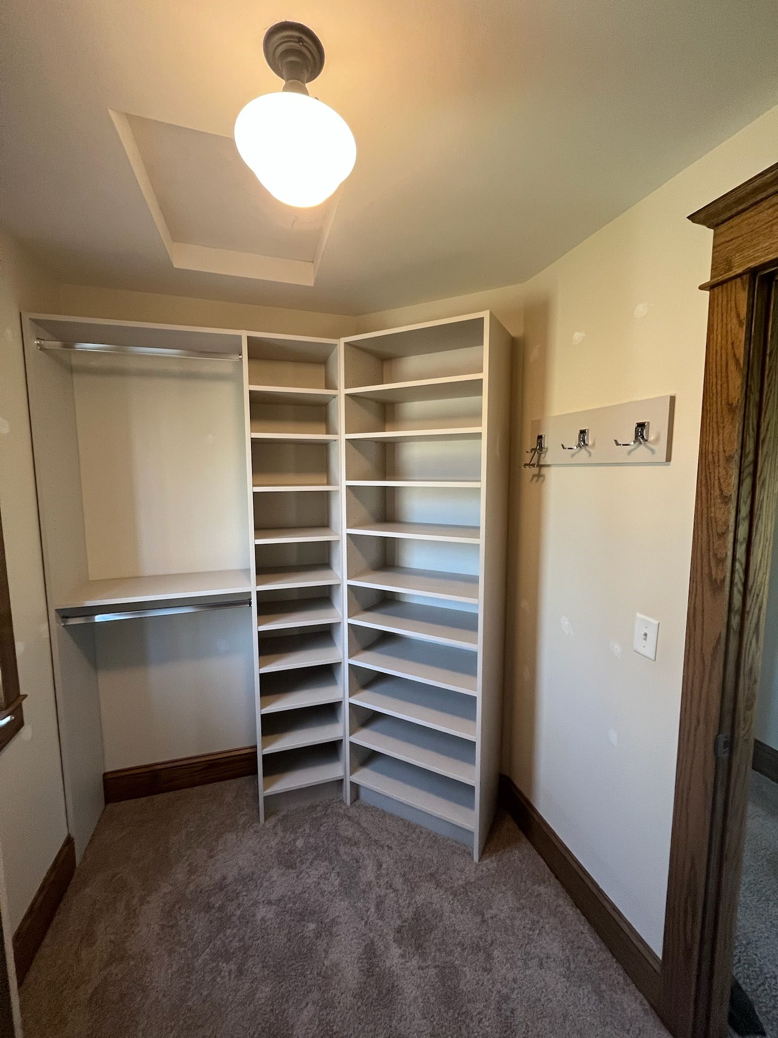 Walk-in closet with white shelving, hanging rod, and carpeted floor under a ceiling light