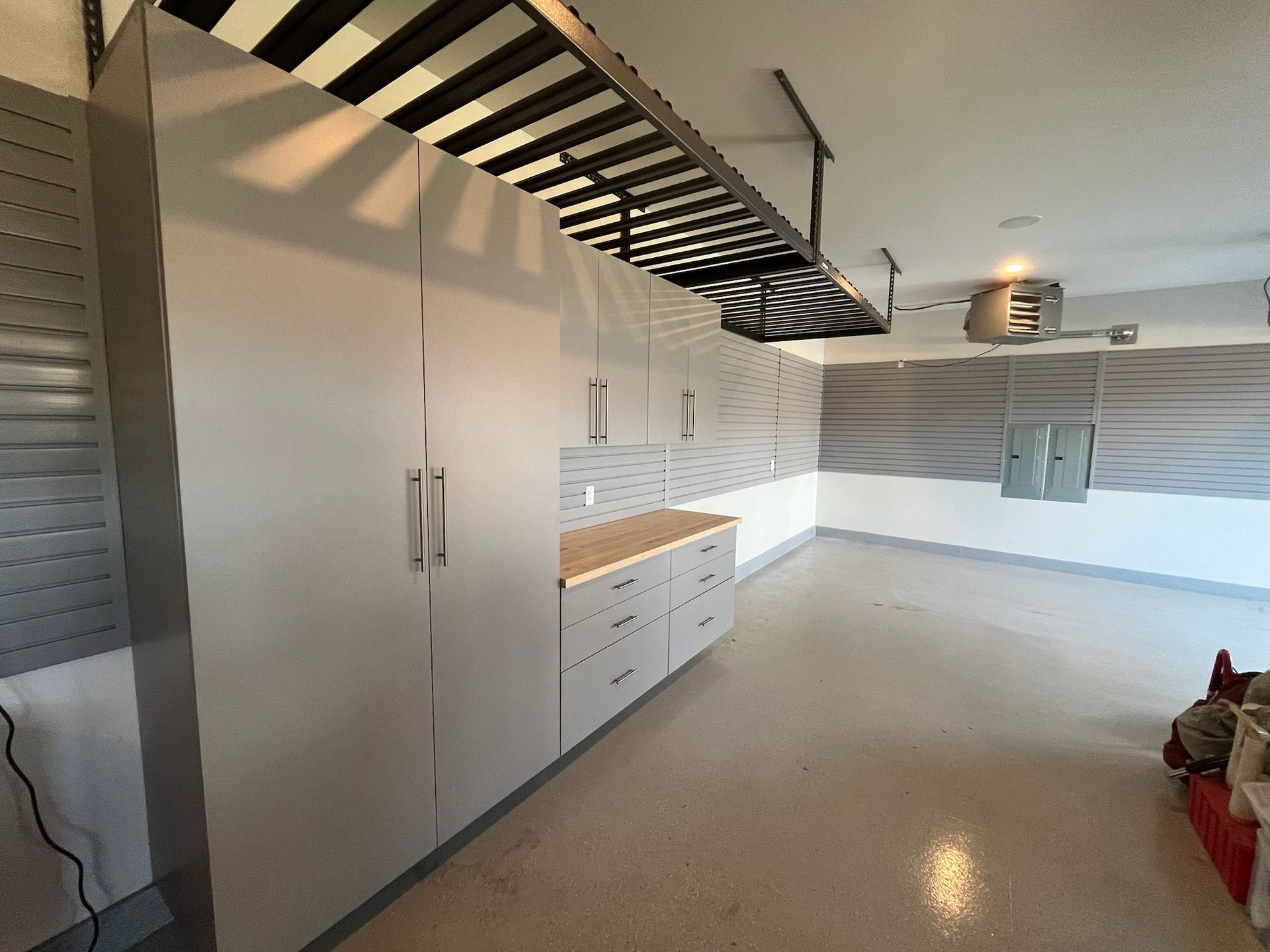 Modern garage with white cabinets, curved metal staircase, and polished concrete floor