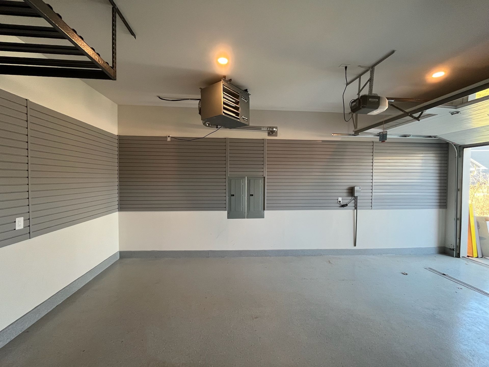 Empty garage interior with gray slat walls, ceiling lights, and concrete floor