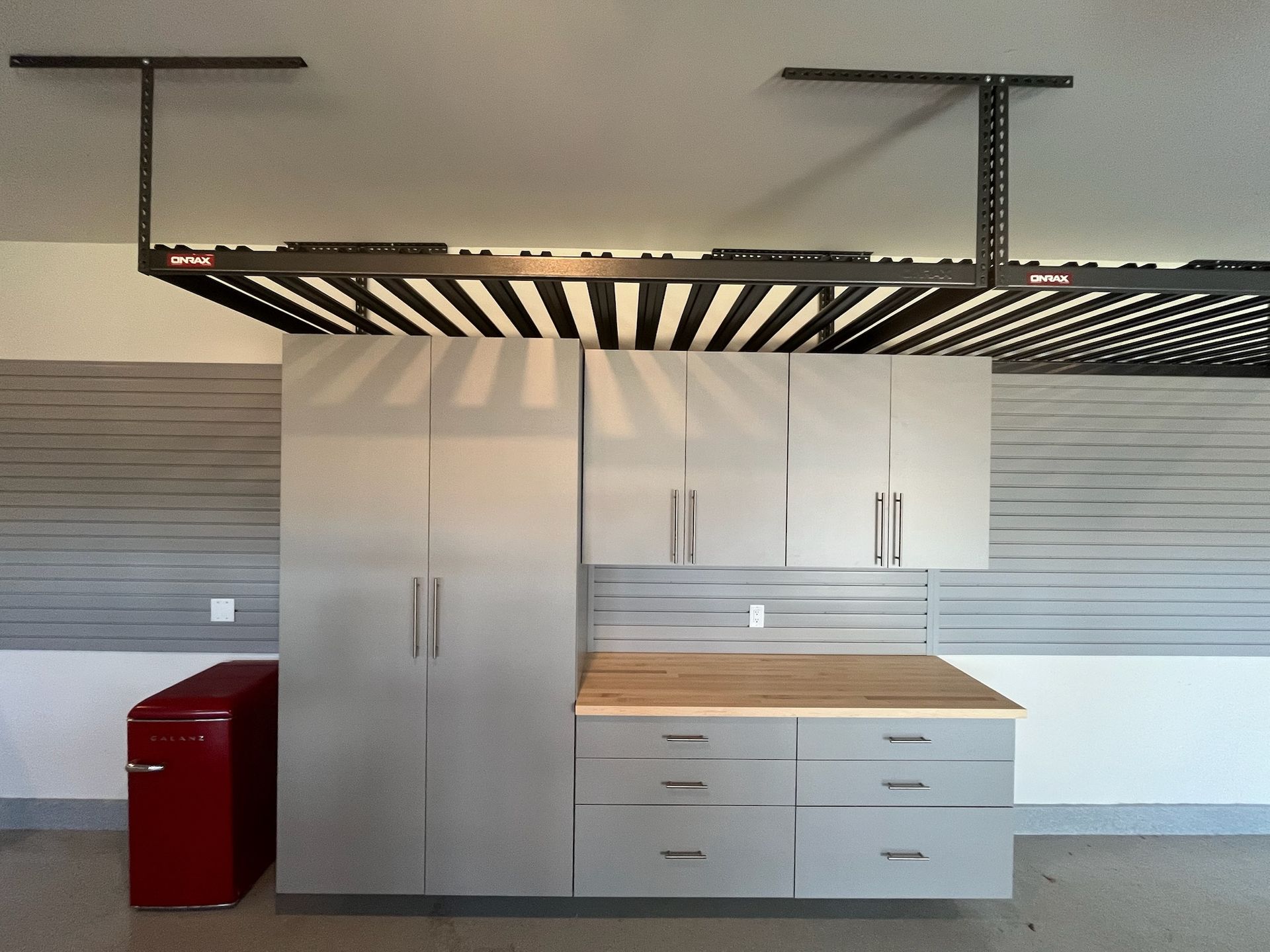 Storage cabinets and drawers beneath a striped awning in a modern interior, with a red bin at left.