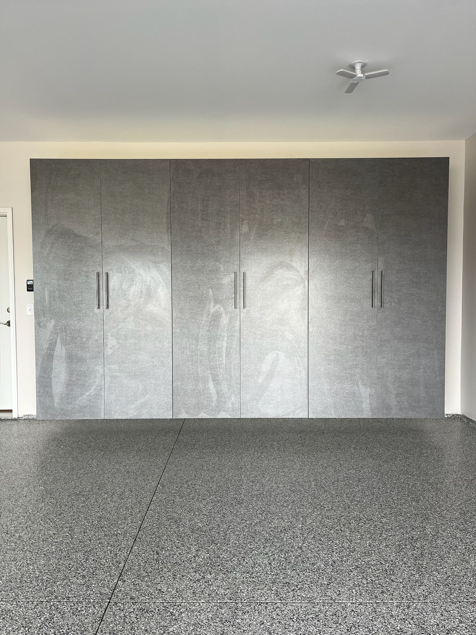 Gray speckled floor and matching wall-length closet doors in a plain room