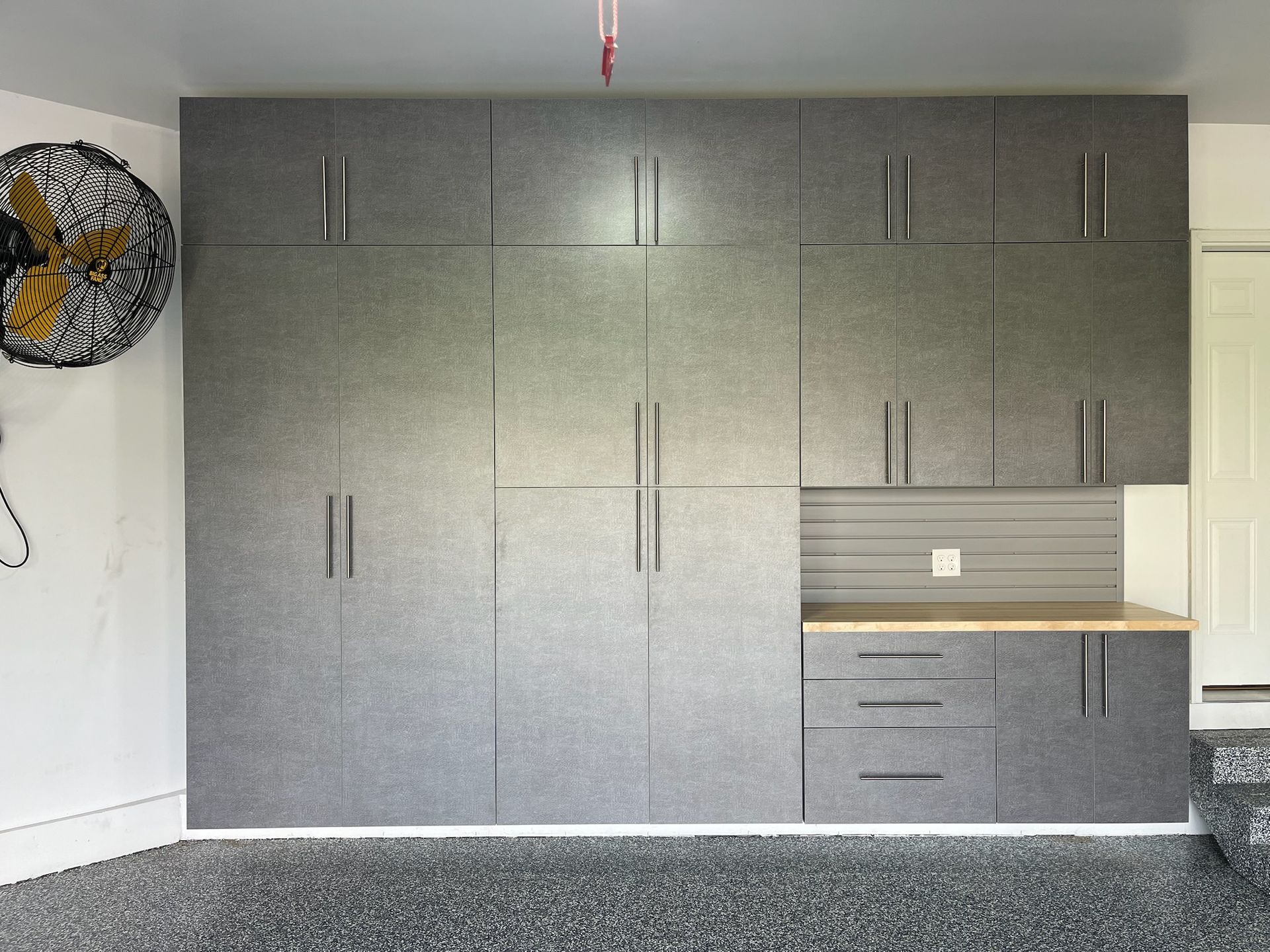 Gray built-in wall cabinets and drawers in a minimalist room with carpet and a small countertop niche.