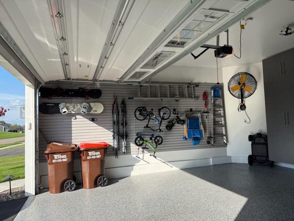 Garage with wall-mounted bikes, trash bins, and storage items in a bright open bay.