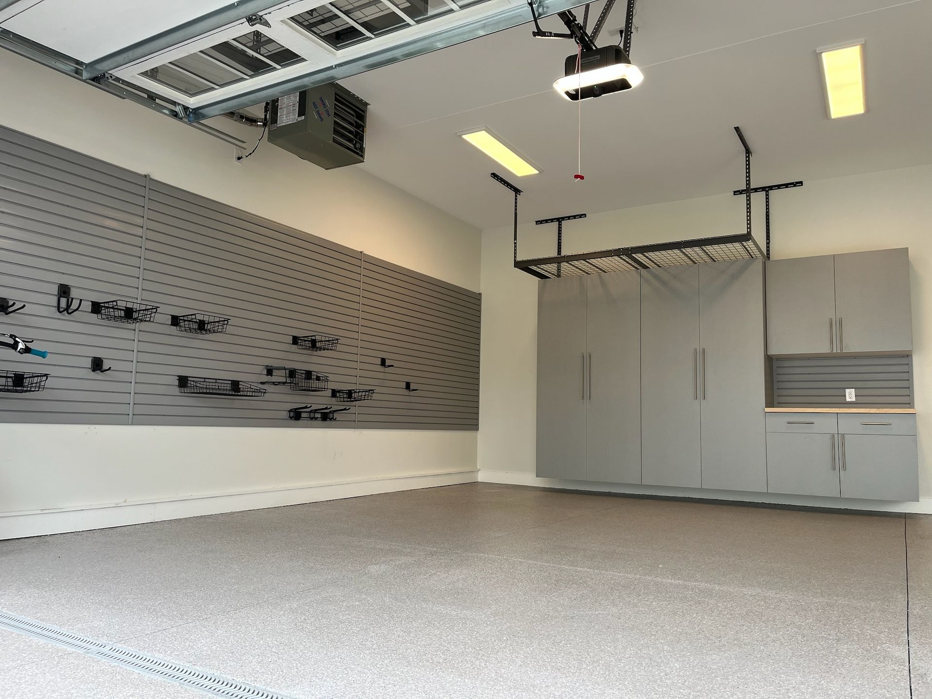 Empty modern garage with overhead storage racks, gray walls, and a speckled floor