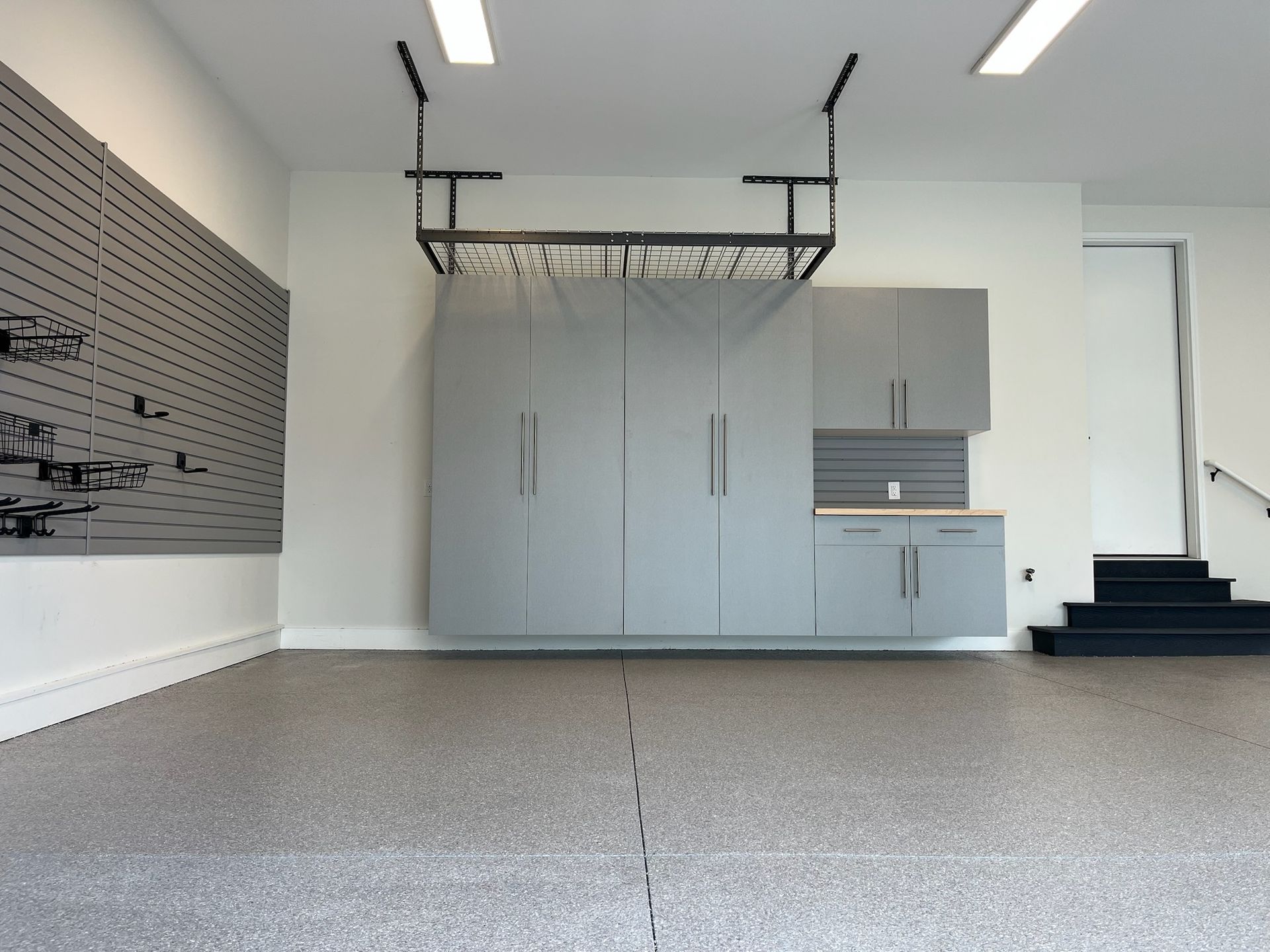 Empty indoor garage with gray storage cabinets, overhead rail system, and concrete floor