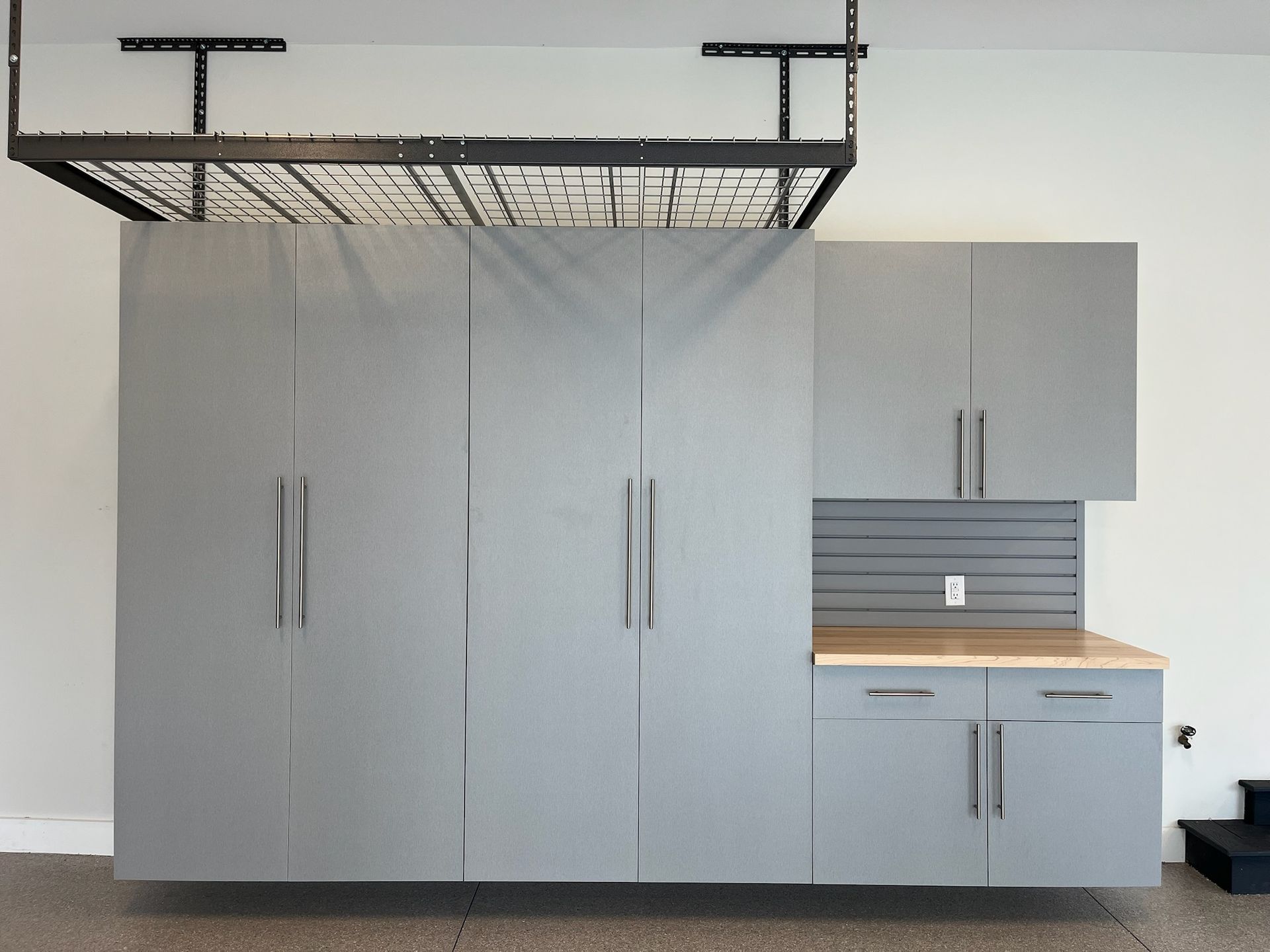 Gray kitchen cabinets with stainless handles, countertop, and open shelving in a minimalist room