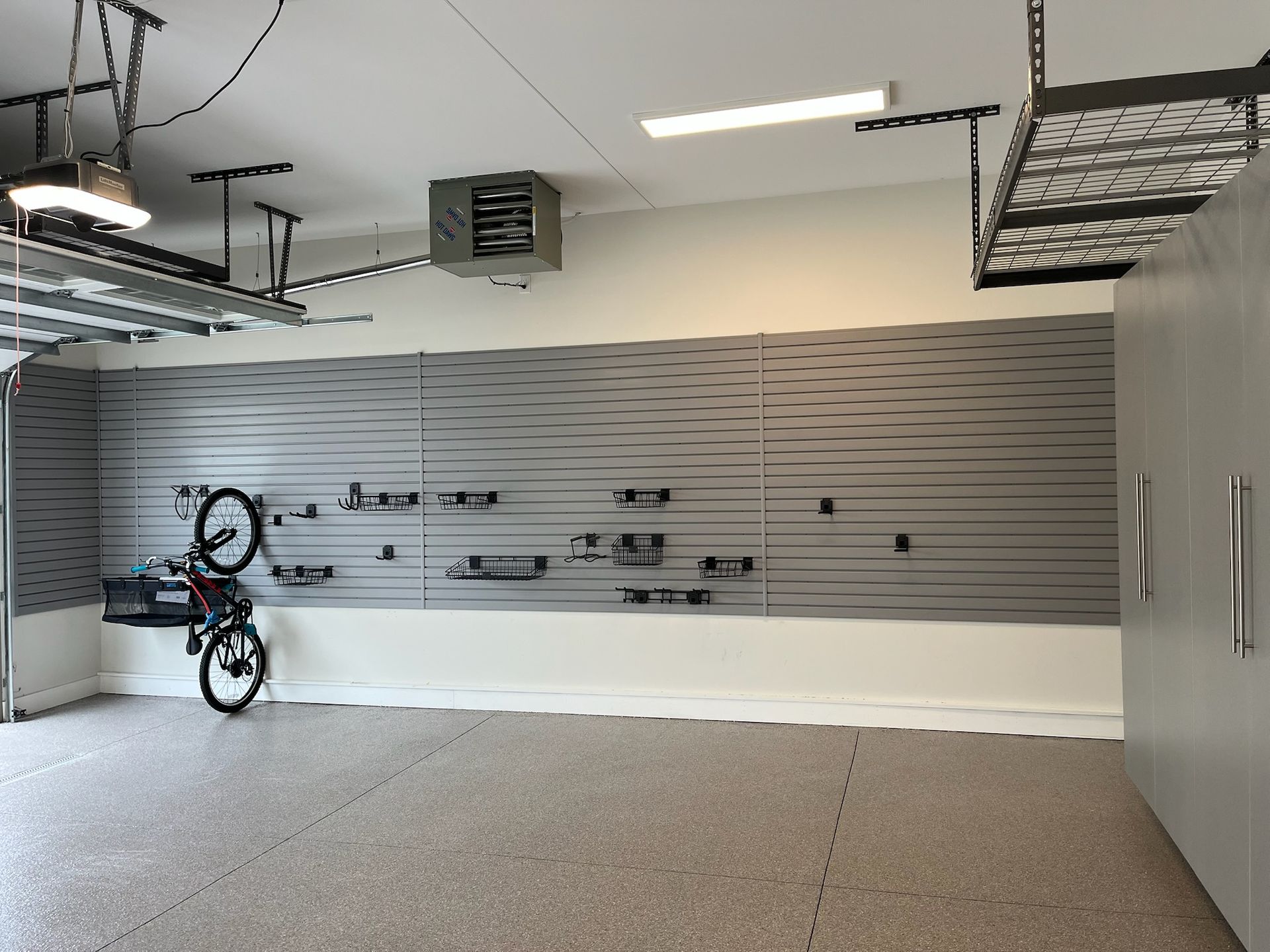 Garage interior with wall-mounted bike racks and a bicycle hanging on the left.